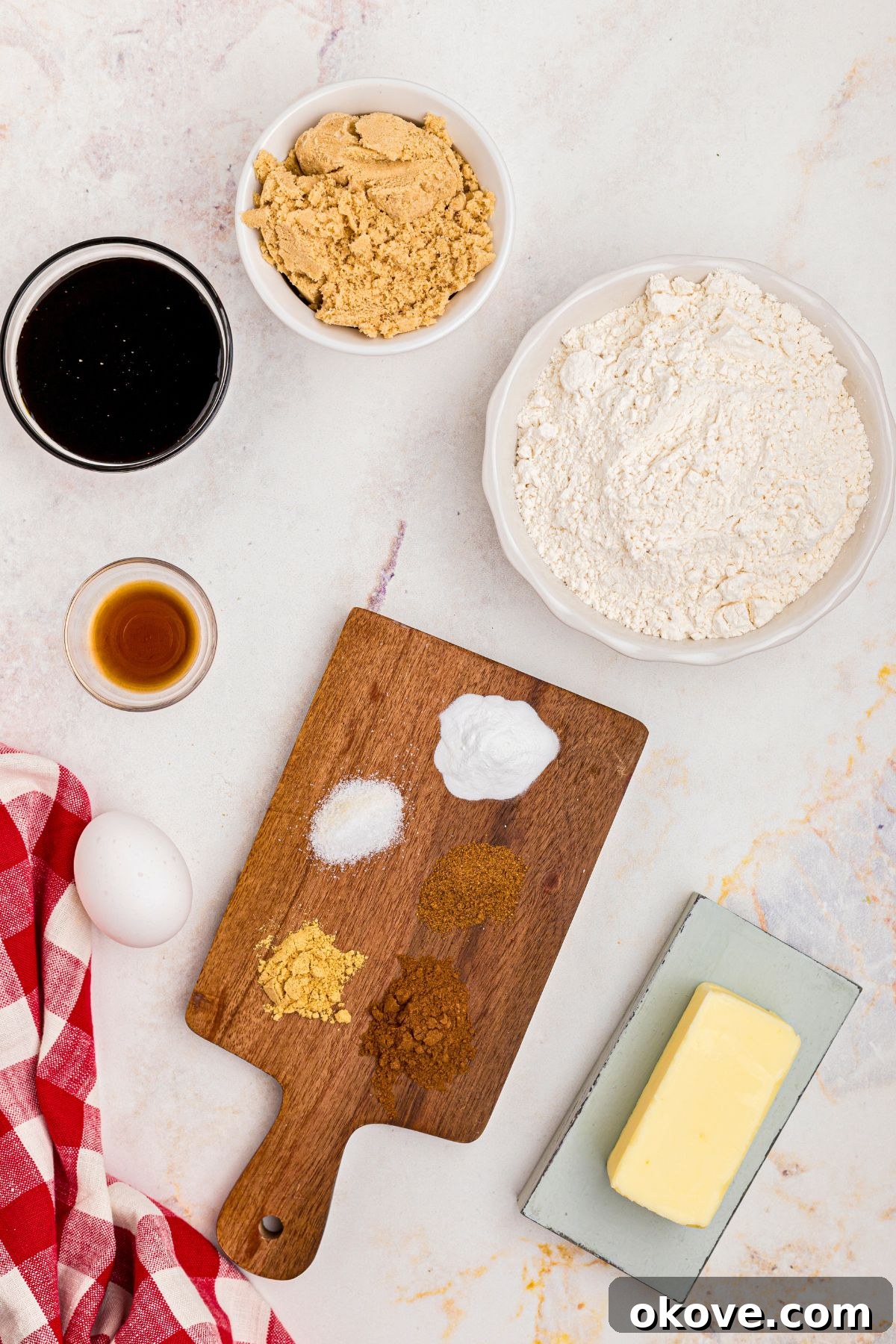 Festive Gingerbread Delights 3 Ingredients needed to make gingerbread cookies measured in small dishes, on a marble table.