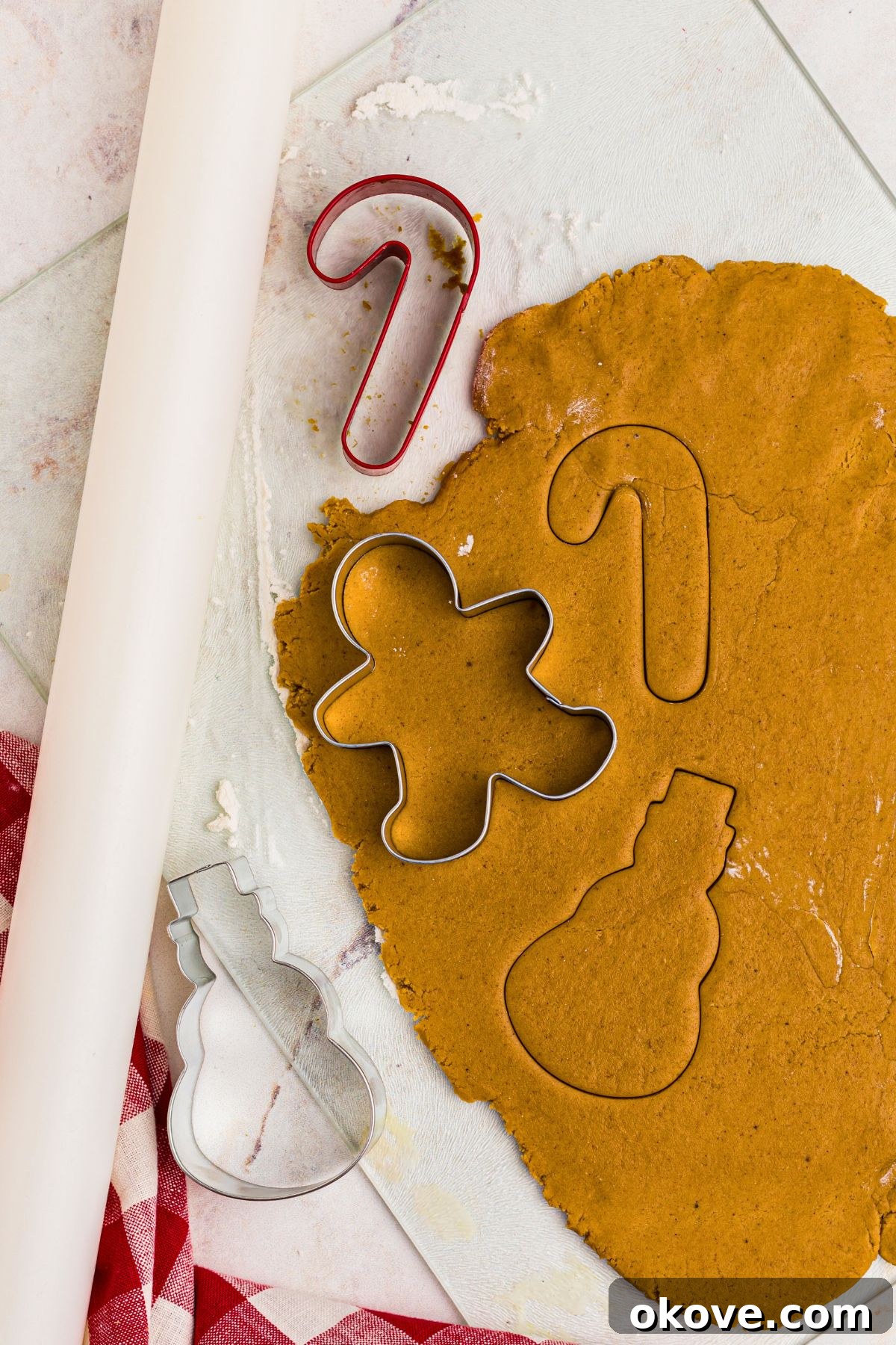 Festive Gingerbread Delights 8 gingerbread cookie dough rolled out and being shaped with cookie cutters.