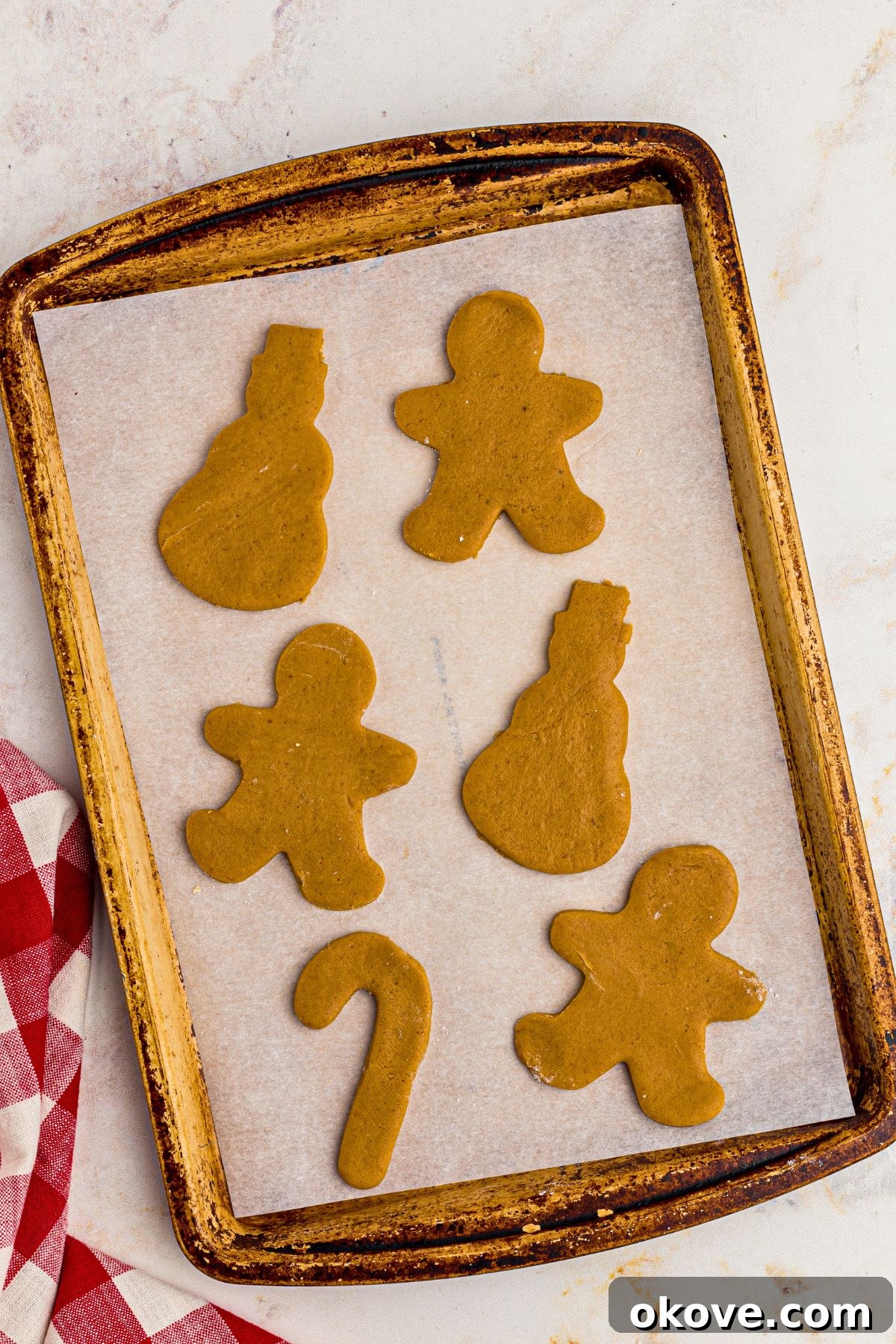 Festive Gingerbread Delights 9 Uncooked gingerbread cookies on a baking sheet lined with parchment paper.