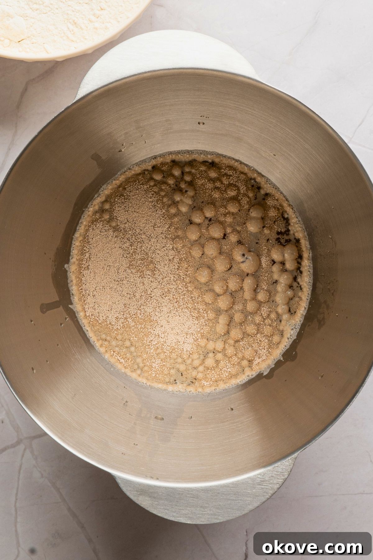 Pillowy Soft Pretzels 4 Yeast activating in warm beer, in a silver bowl.