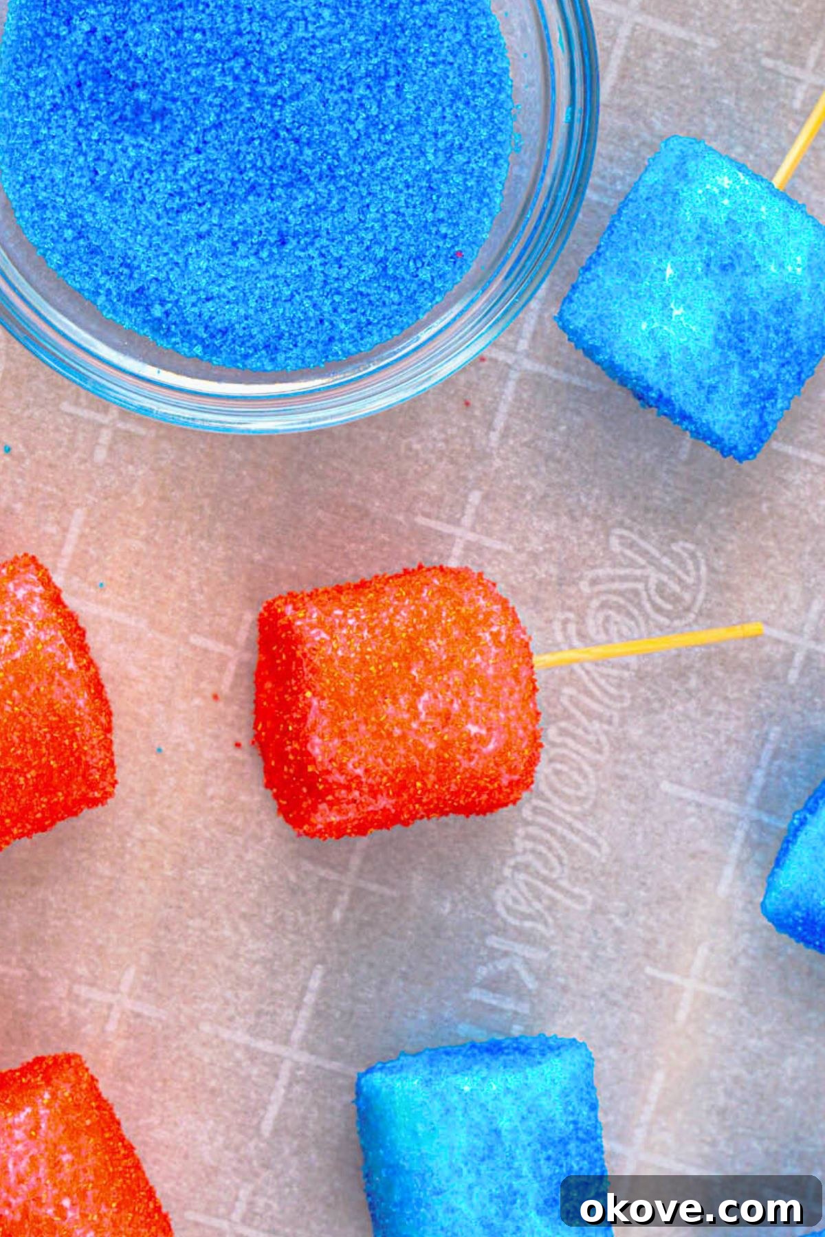 Red, White, and Gooey S'mores Dip 4 A marshmallow on a toothpick, freshly dipped in water and then rolled in red sanding sugar, glistening with color.