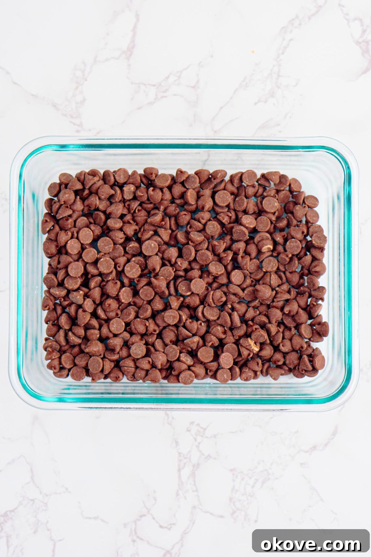 Red, White, and Gooey S'mores Dip 7 Chocolate chips spread evenly across the bottom of a clear glass baking dish, forming the base of the dip.
