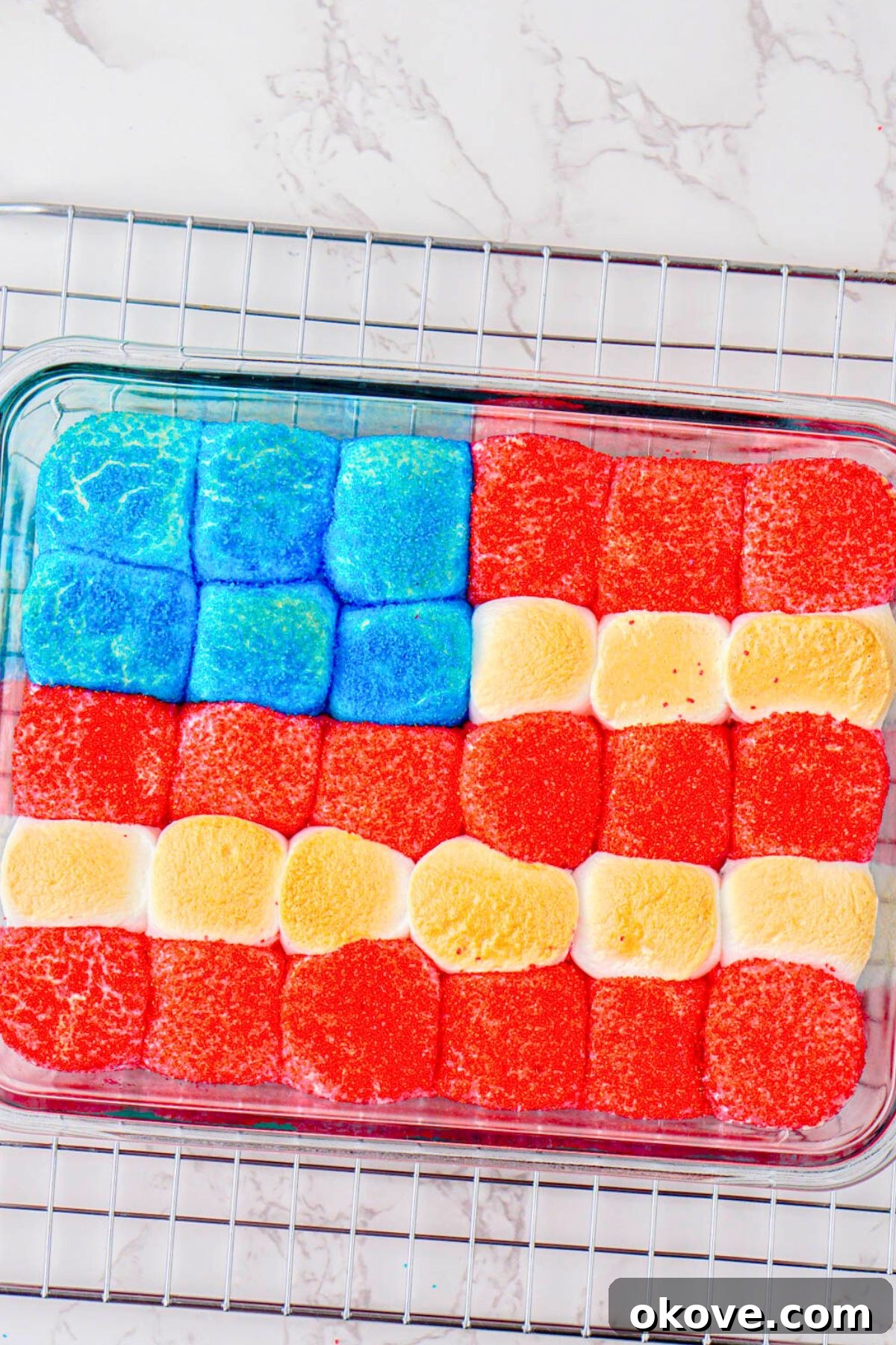 Red, White, and Gooey S'mores Dip 10 A close-up view of the baked Patriotic S'mores Dip, showcasing perfectly toasted red, white, and blue marshmallows over melted chocolate in a clear baking dish.