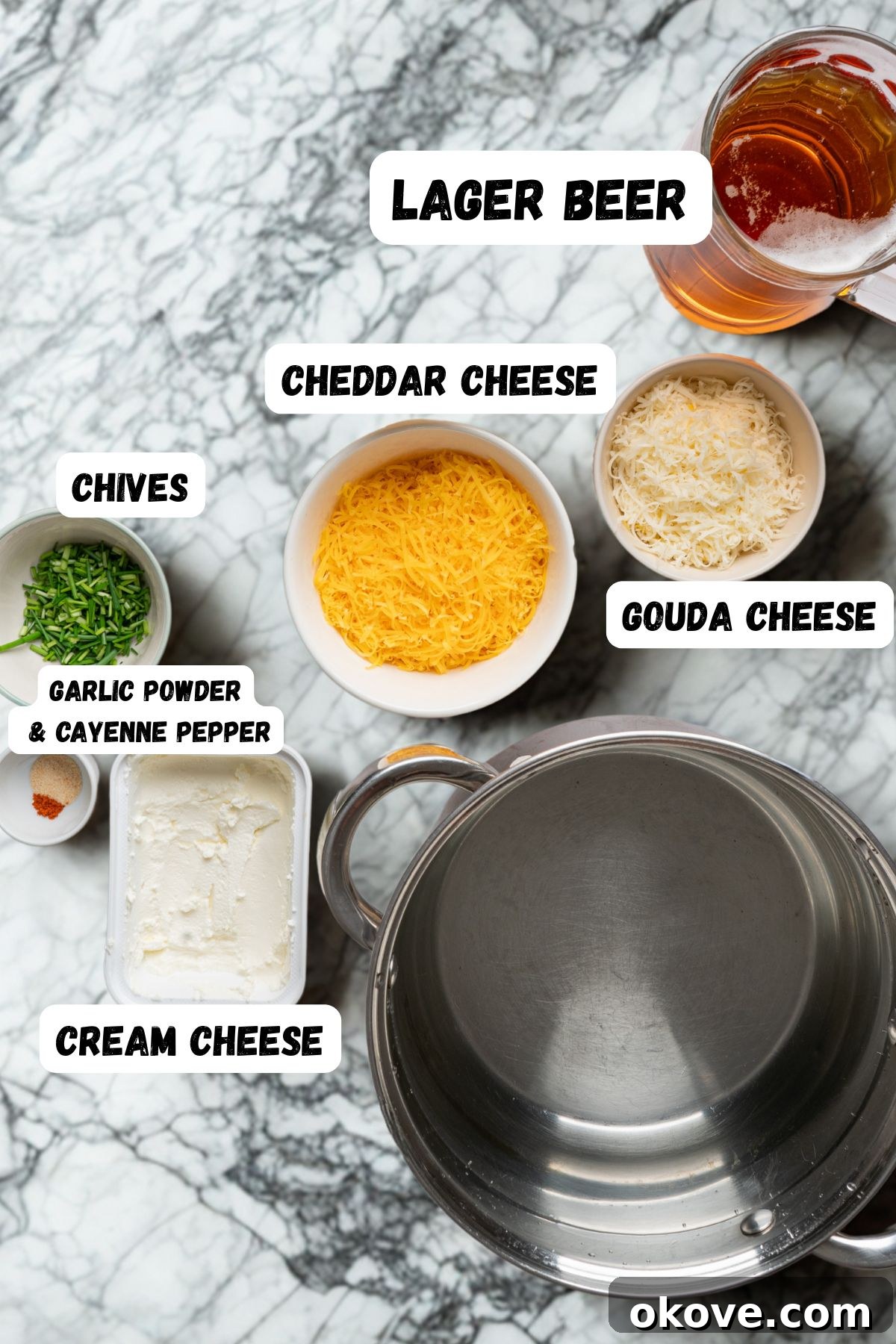 Cream cheese, shredded sharp cheddar and gouda cheese, Dijon mustard, and common spices measured in small bowls on a marble countertop, meticulously arranged and ready for mixing.