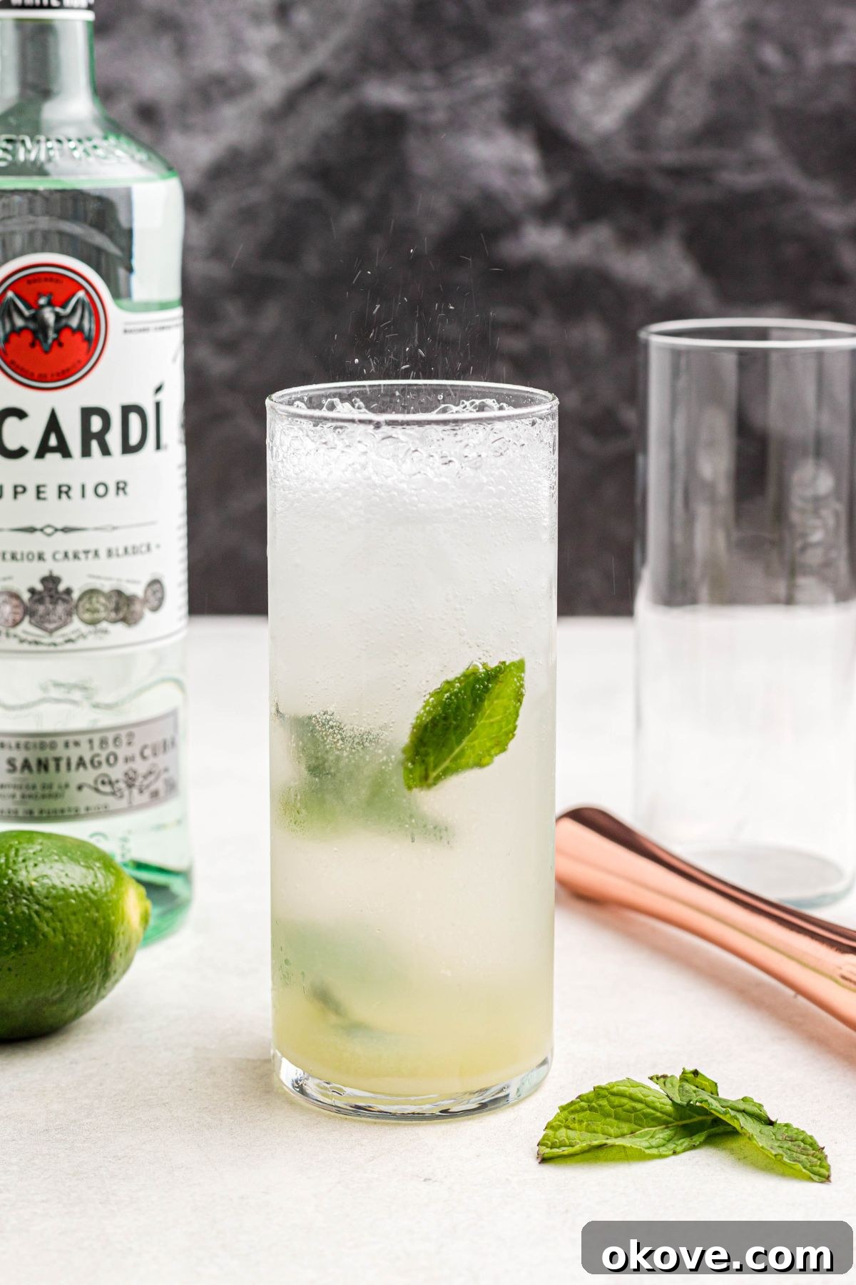 Sparkling club soda being added to top off a mojito cocktail in a tall glass, creating effervescence.
