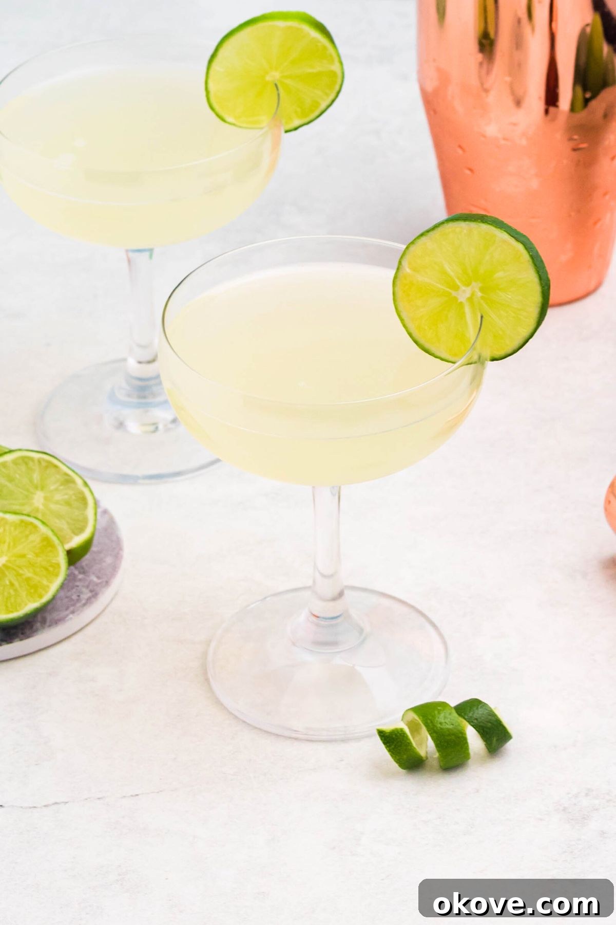 Tropical Rum Delight 6 Small glass filled with drink, garnished with lime wheel, on a marble table with limes and lime curls on the table.