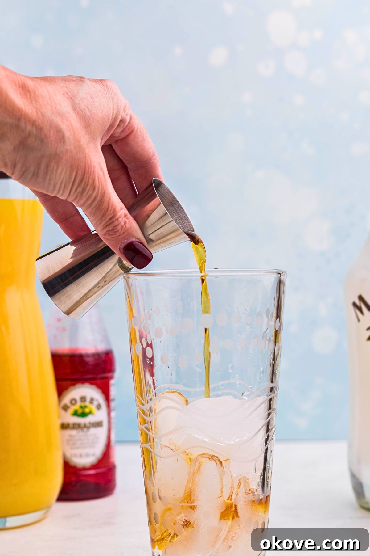 Ingredients being poured into cocktail shaker with ice. 