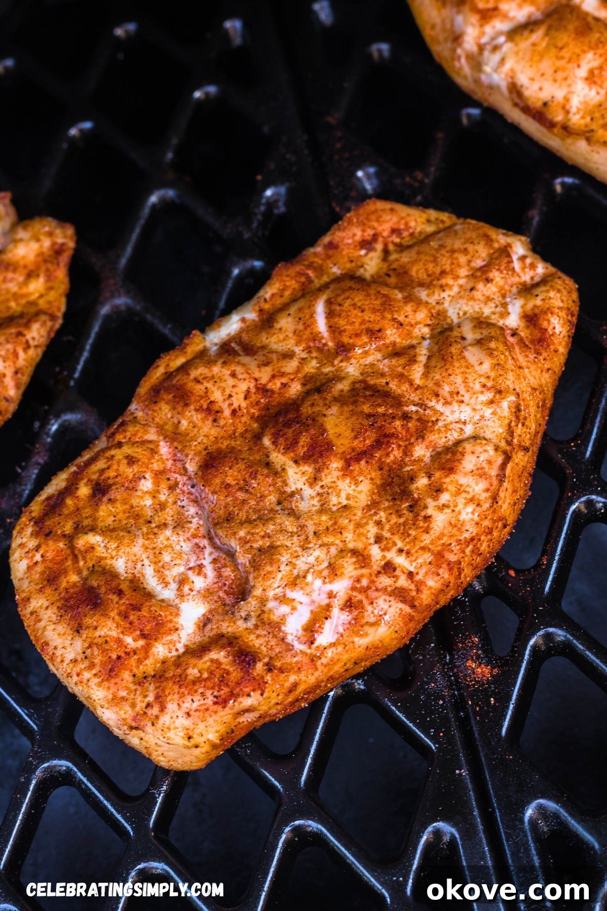 Seasoned chicken breast cooking on a grill rack inside a smoker, absorbing the smoky flavor.