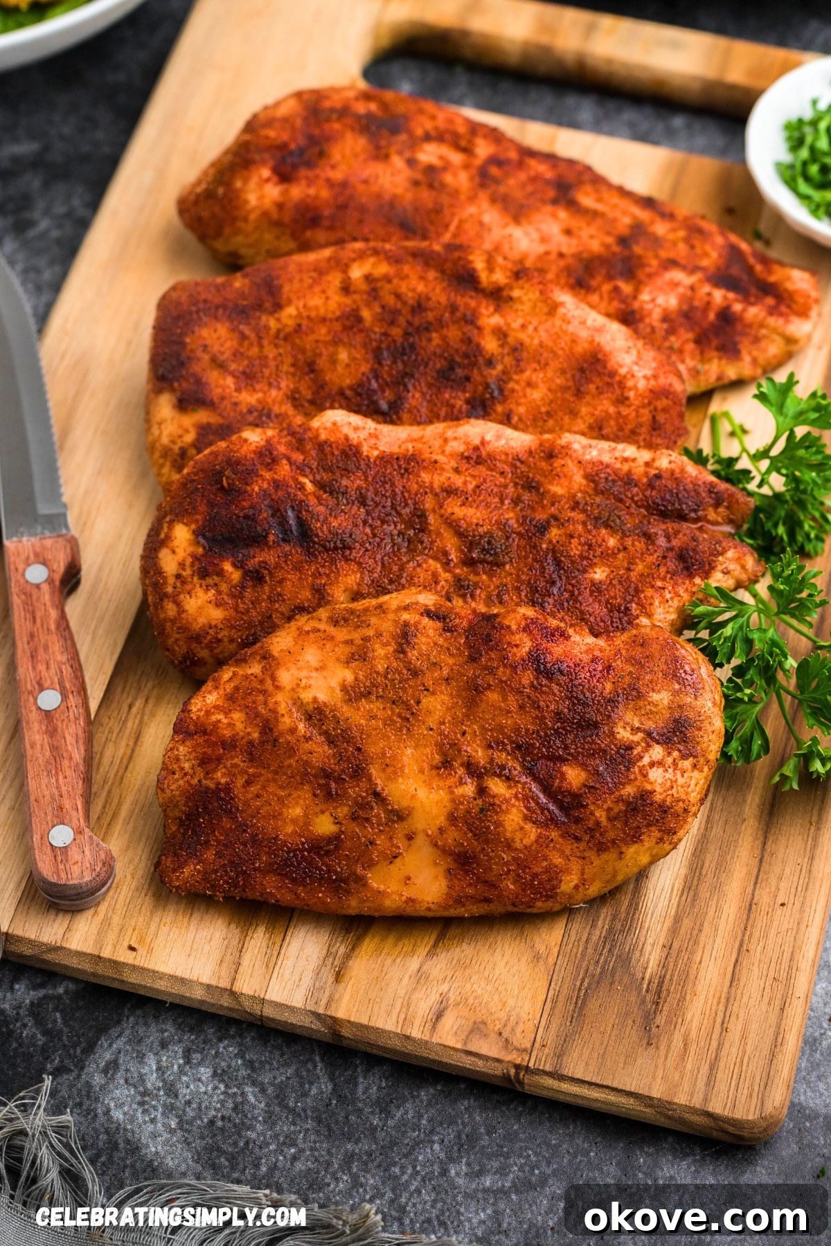 Smoked chicken breasts resting on a wooden cutting board, allowing the juices to redistribute for maximum tenderness.