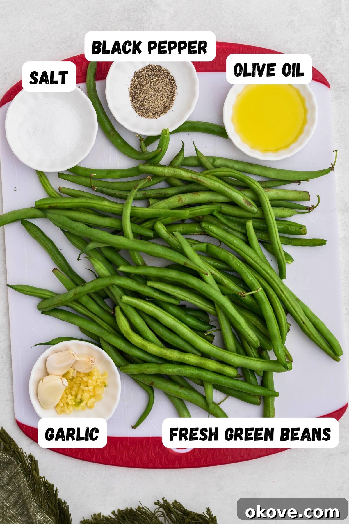 Crispy Roasted Green Beans 3 Fresh green beans, olive oil, kosher salt, and ground black pepper measured into small bowls on a marble surface, ready for preparation.