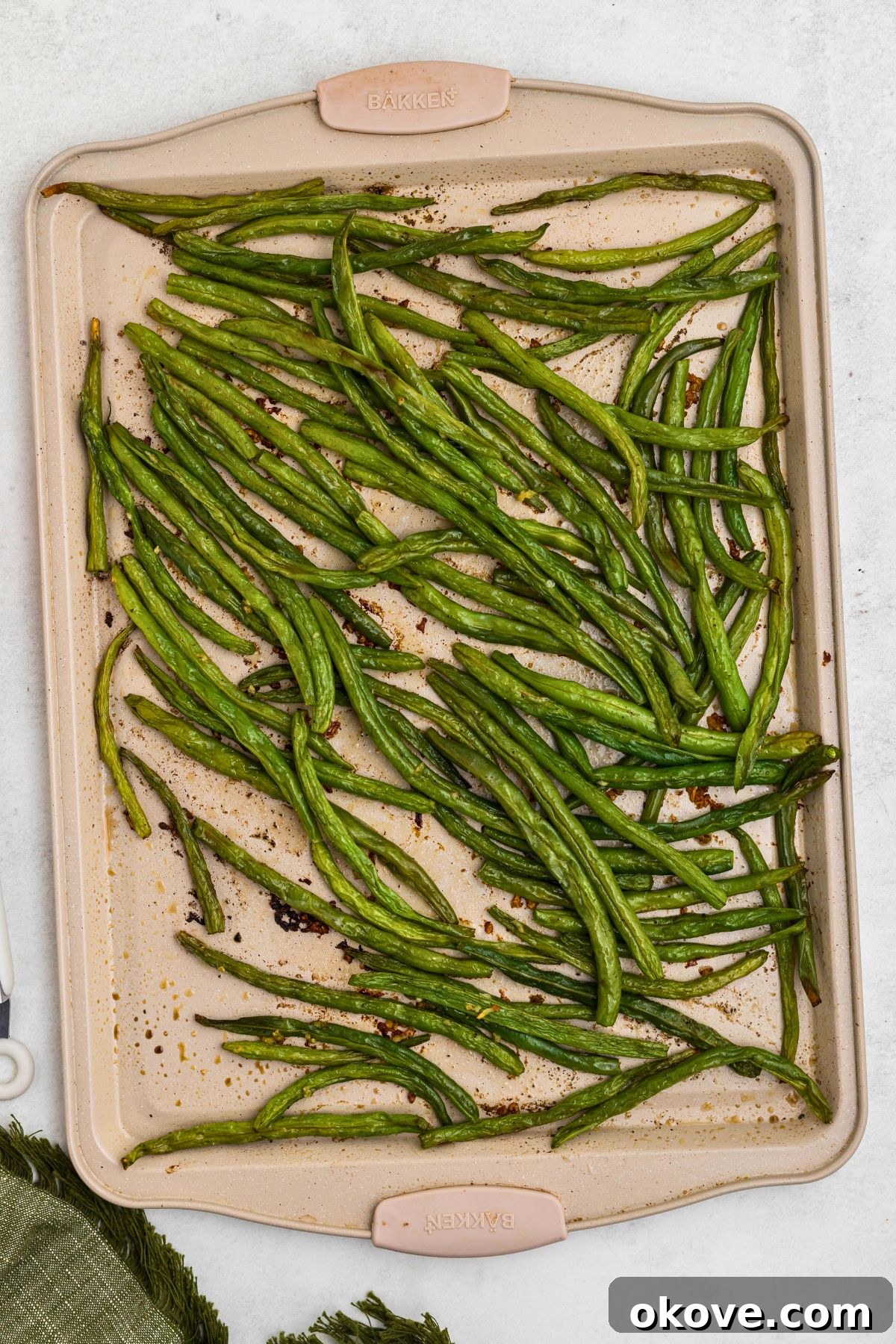 Crispy Roasted Green Beans 6 Crispy, golden-edged roasted green beans cooling on a baking sheet after being removed from the oven.