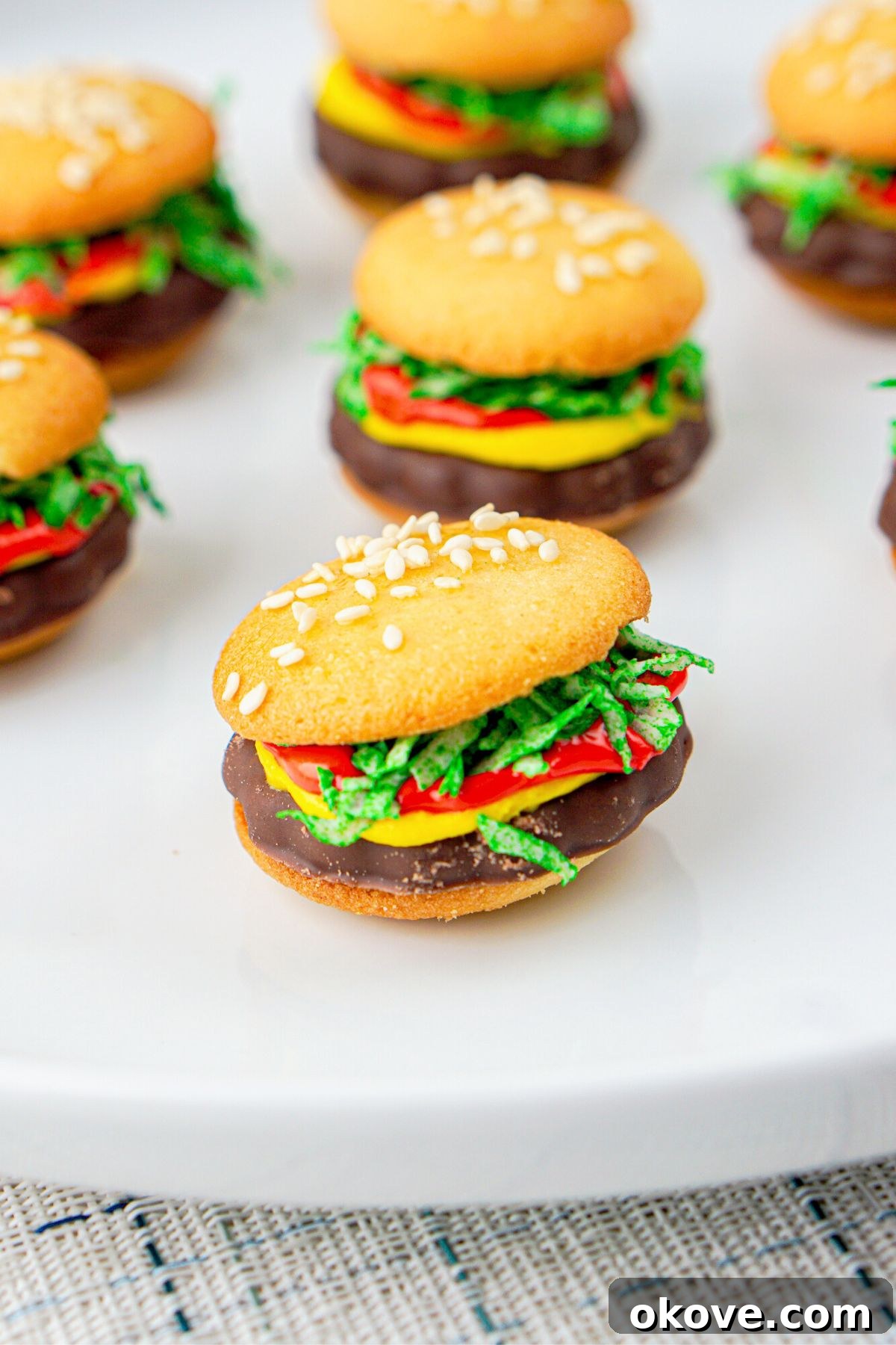 Dessert Burgers 2 Delicious vanilla wafer cookies used as buns, with colorful frosting, green coconut, and rich chocolate cookies in between them to create a charming mini burger dessert. These no-bake treats are perfect for any celebration.