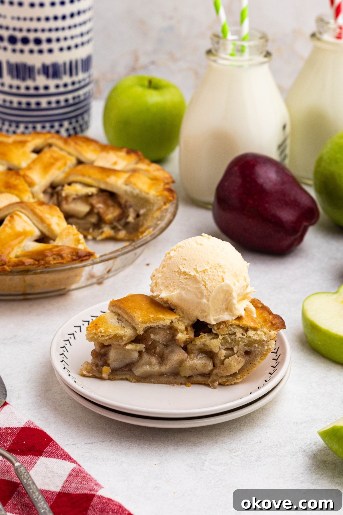 A slice of pie on small white plate with a scoop of vanilla ice cream on top. 