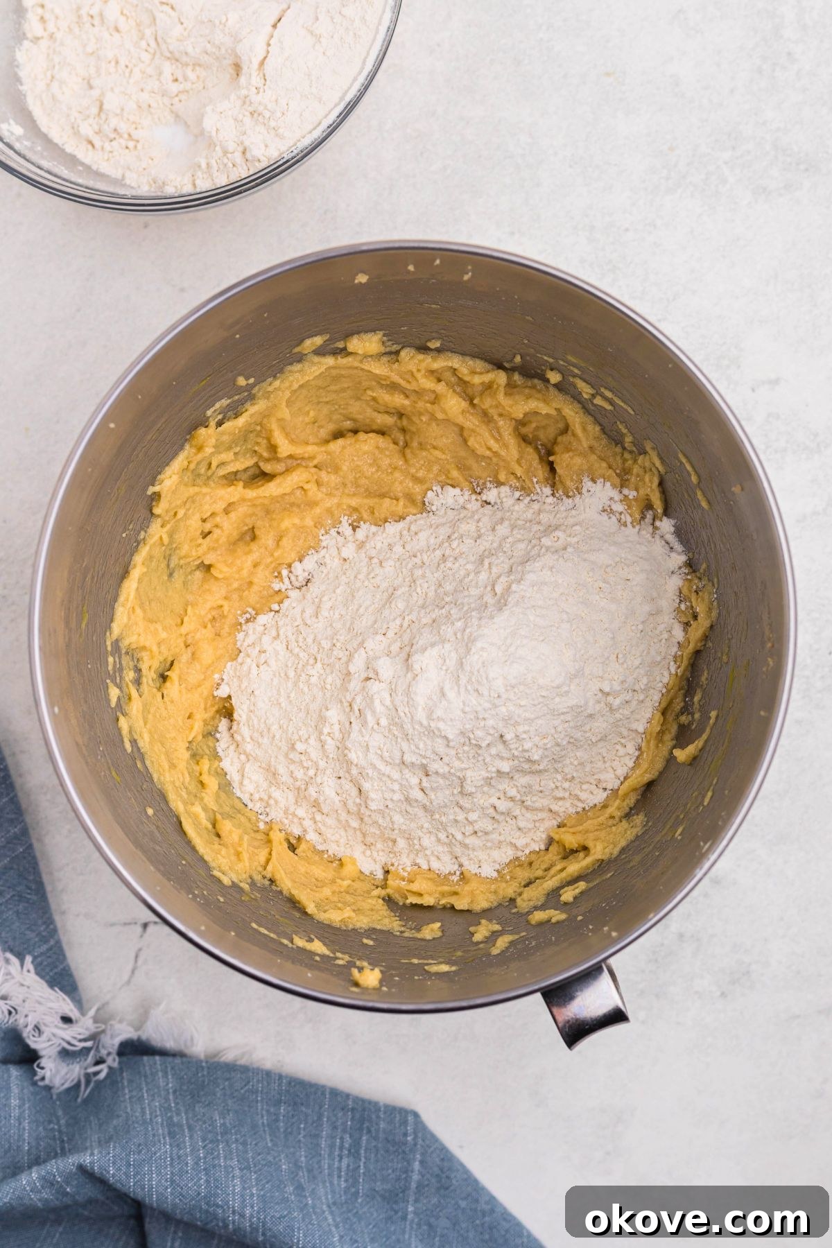 Ultimate Chocolate Chip Bars 6 Flour and other dry ingredients being mixed into butter and sugars, in a silver bowl.