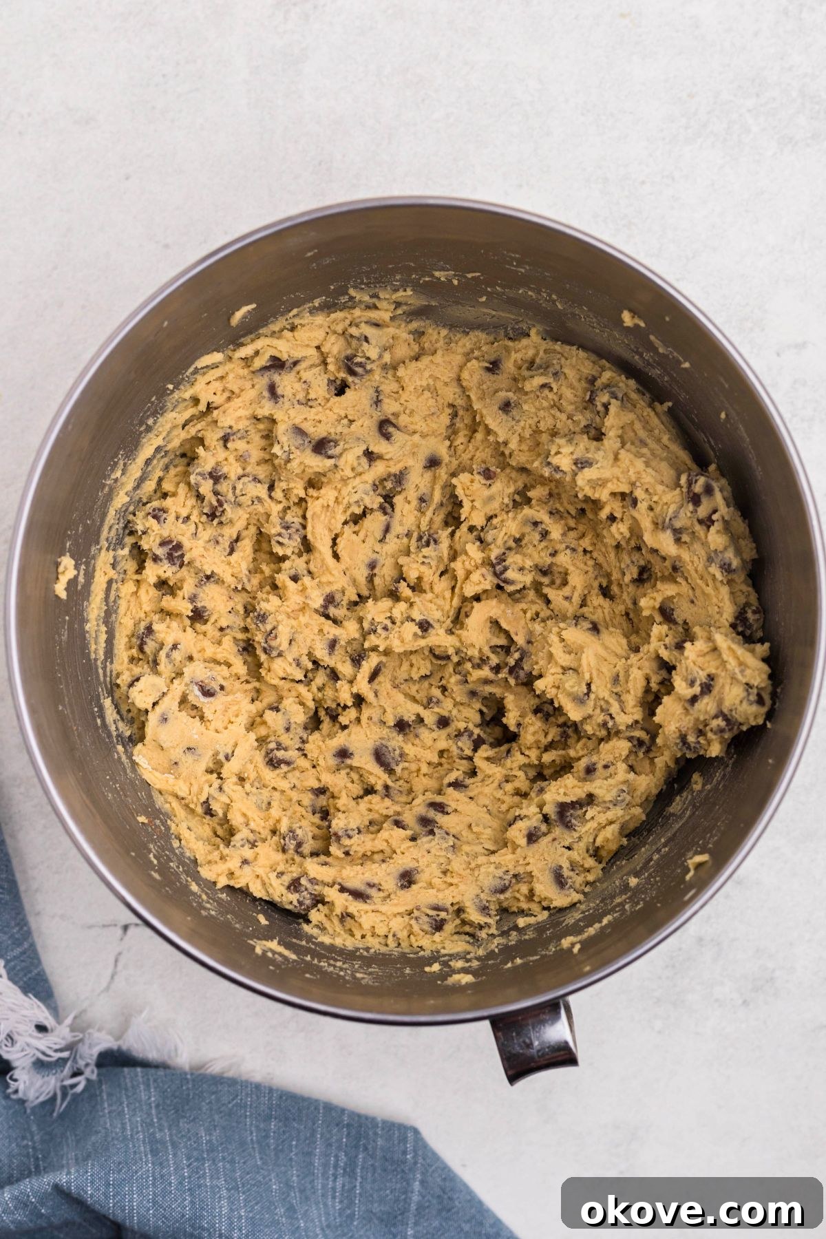 Ultimate Chocolate Chip Bars 7 Soft cookie dough with chocolate chips mixed into the dough, in a silver mixing bowl.