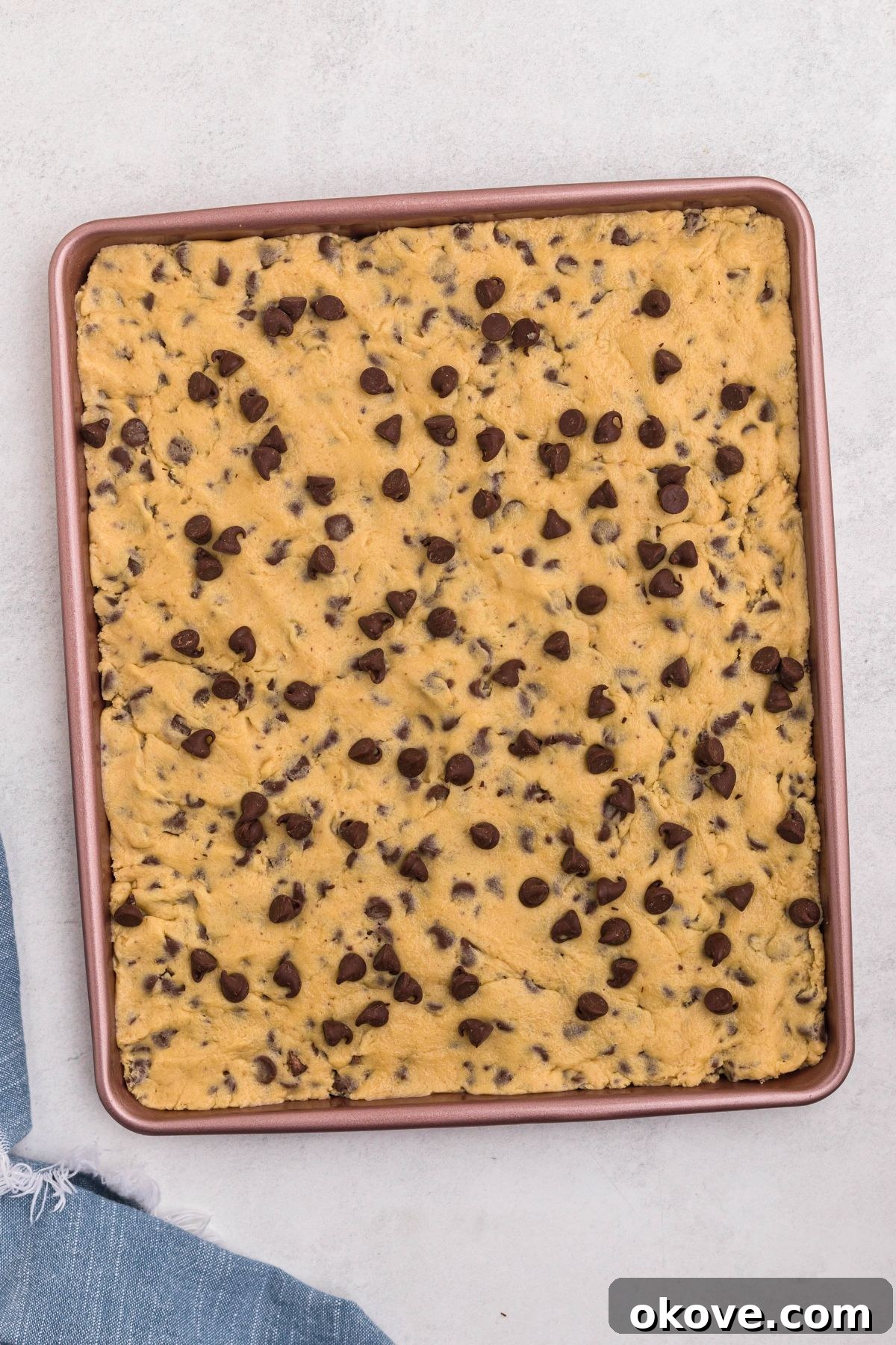 Ultimate Chocolate Chip Bars 8 Uncooked chocolate chip cookie dough spread evenly in a baking pan.