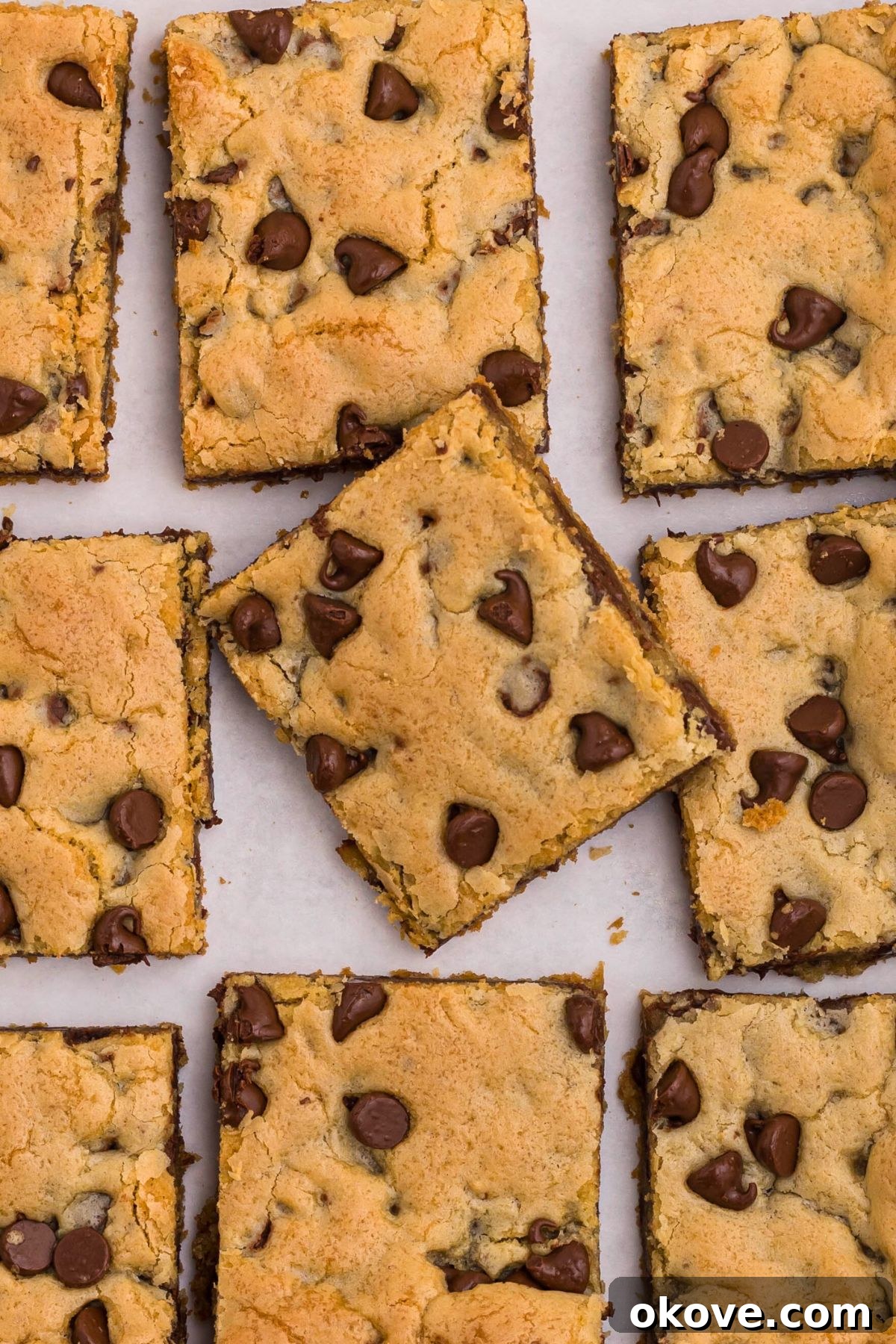 Ultimate Chocolate Chip Bars 10 Chocolate chip cookie bars cut into slices, on a white marble table.