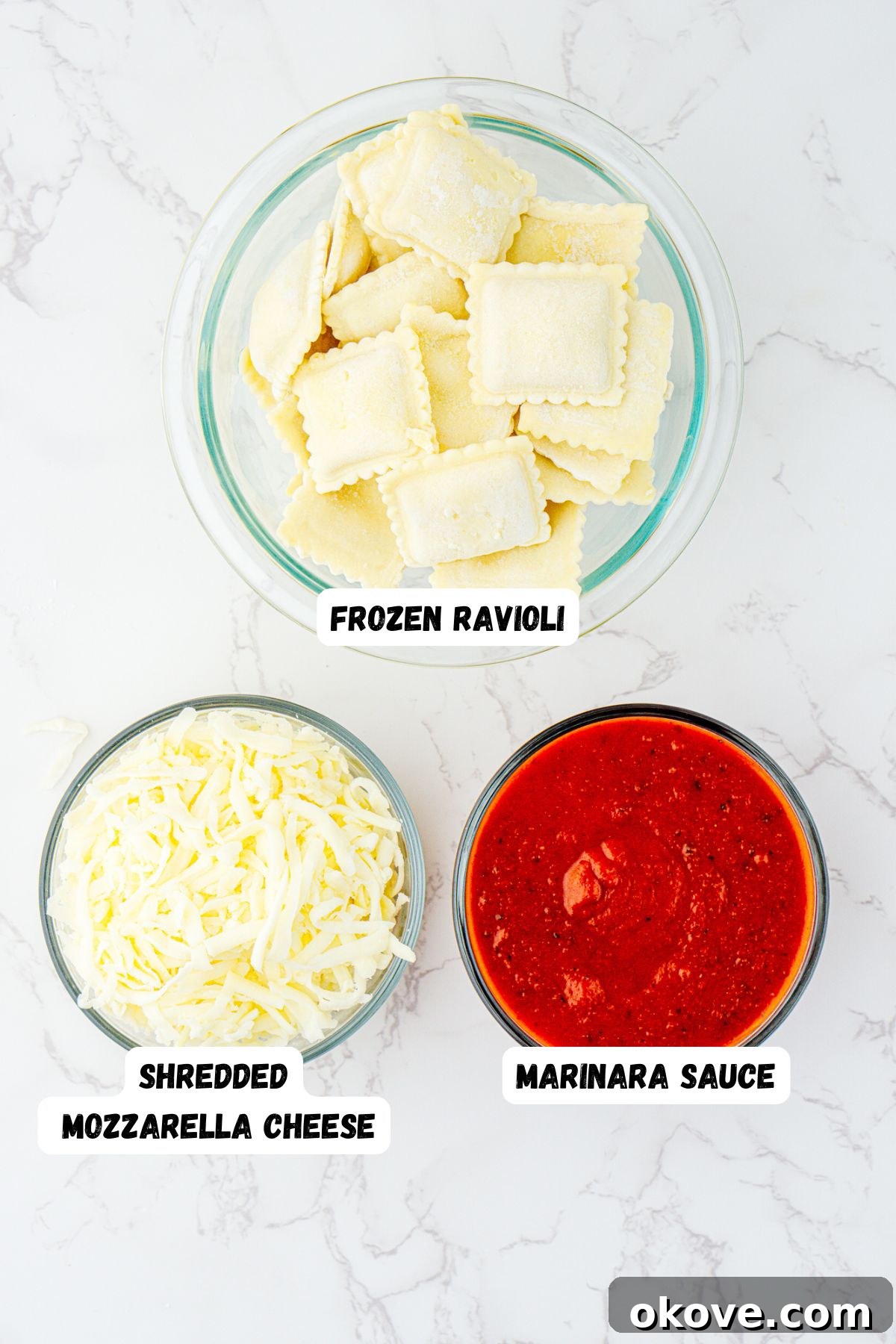 Stacked Ravioli Lasagna 3 Ingredients needed to make ravioli lasagna measured in clear glass bowls on a white marble table.