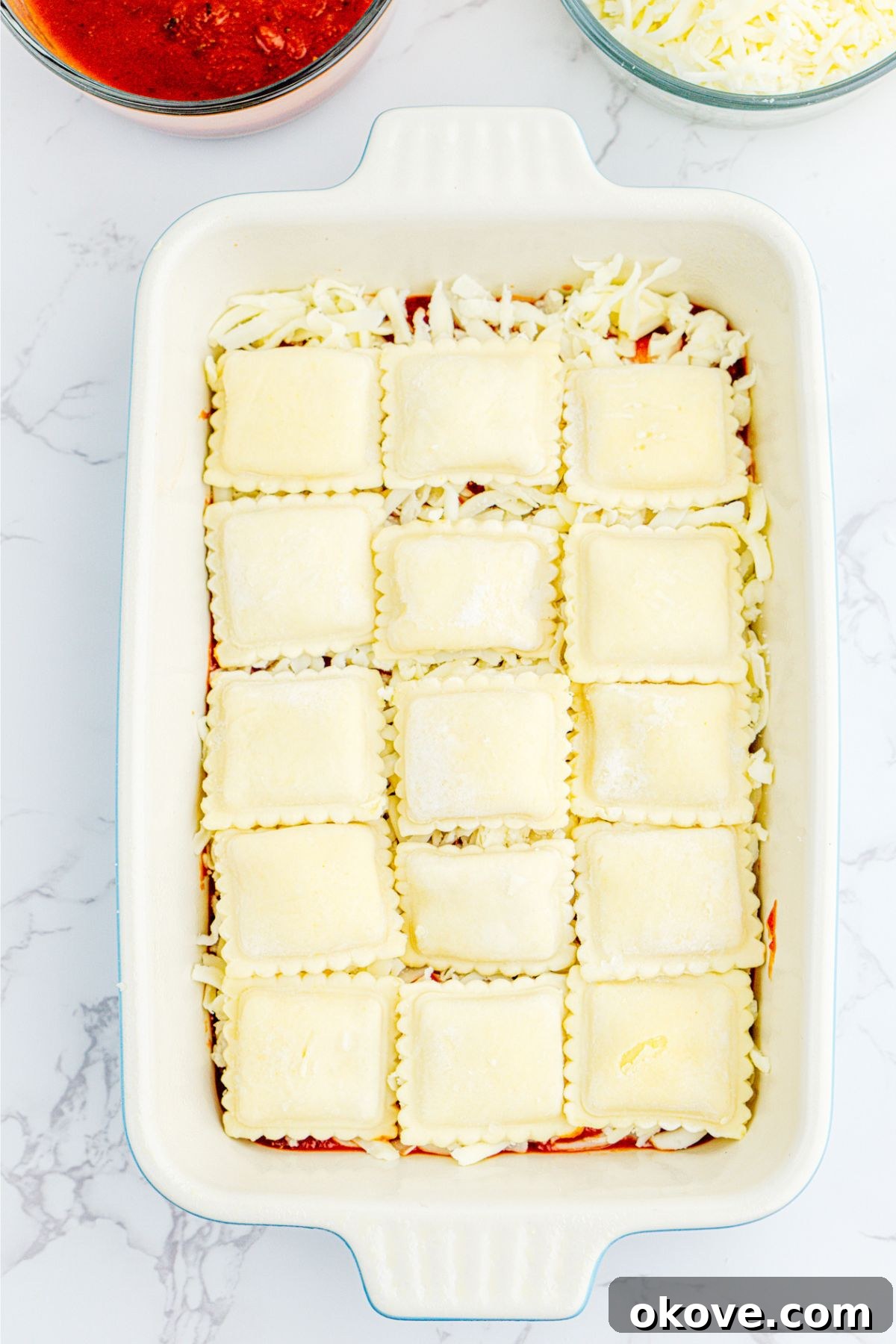 Stacked Ravioli Lasagna 5 White rectangle dish filled with layers of sauce, ravioli, and shredded mozzarella cheese.