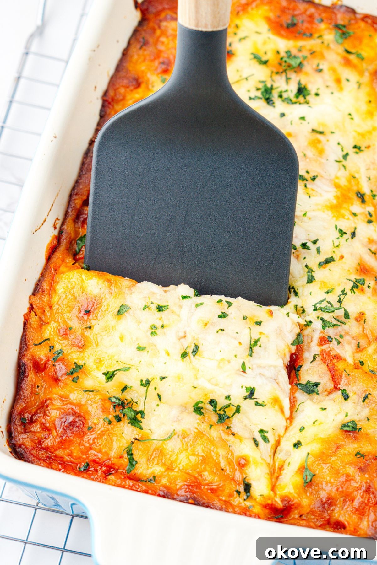 Stacked Ravioli Lasagna 8 White casserole dish of ravioli lasagna with a slice being scooped out with a spatula.