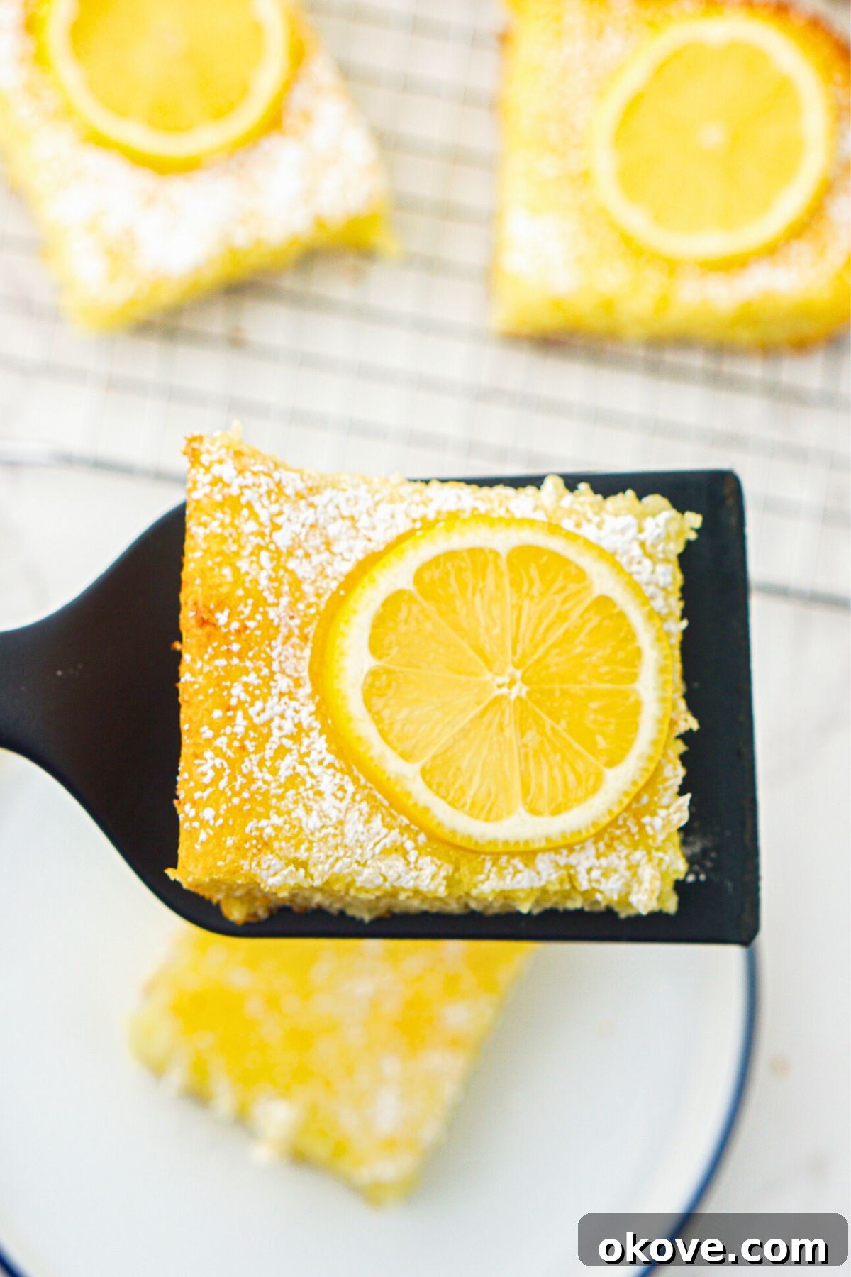 Effortless Two-Ingredient Lemon Bars 8 Bright yellow lemon bars after baking, with one being lifted to serve on a spatula. A perfect, easy dessert.