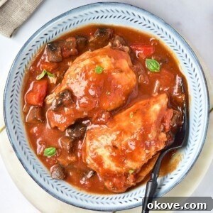Deliciously Simple Slow Cooker Chicken Cacciatore 9 Cooked chicken cacciatore in a red sauce, with seasonings, in a white bowl.