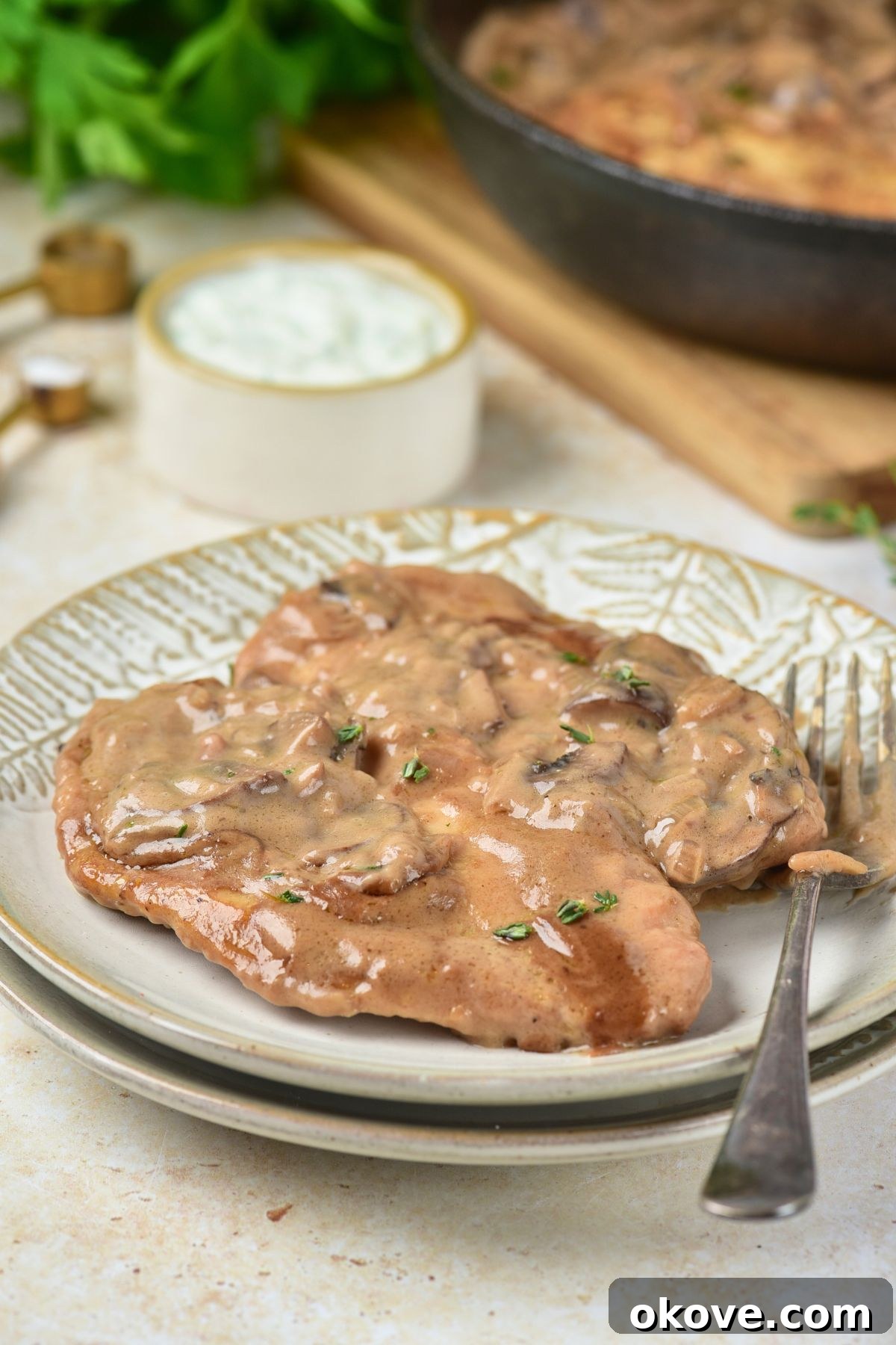 Chicken marsala served on white plates, with fork on the side.