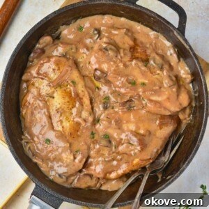 Creamy sauce over 3 pieces of cooked chicken in a large black skillet.