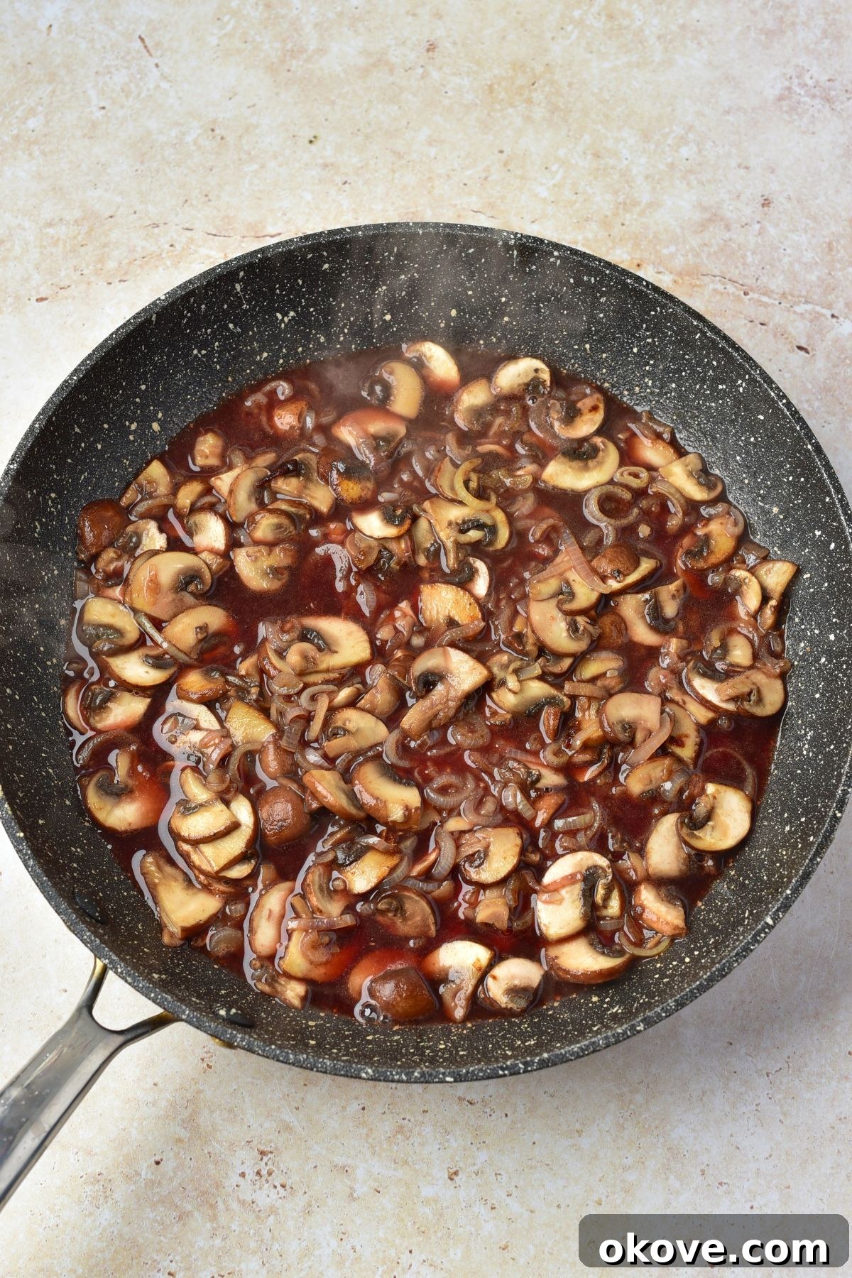 Wine being added to skillet with mushrooms and shallots, to make sauce for chicken marsala.