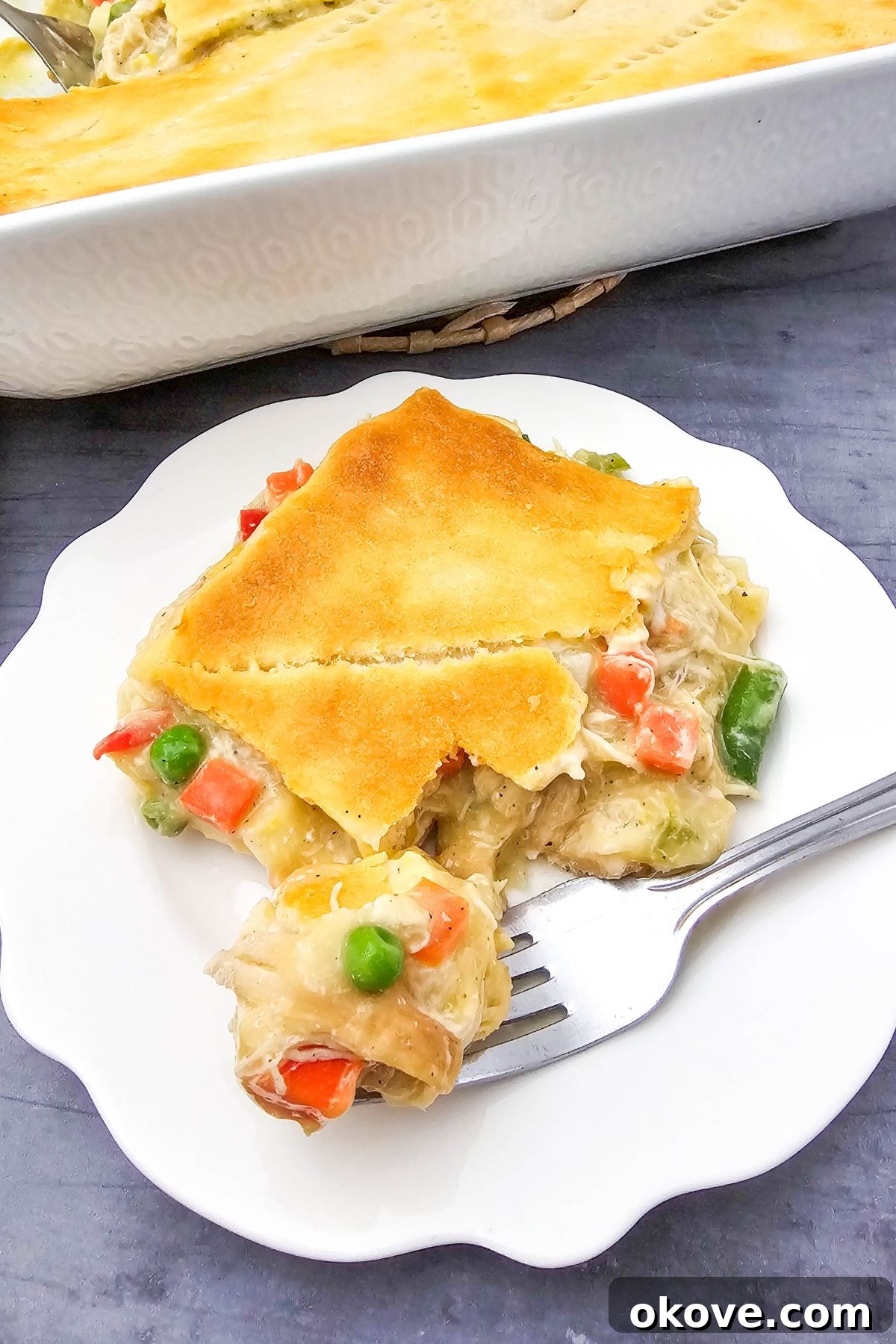 Homestyle Chicken Pot Pie Bake 2 A golden-crusted slice of baked chicken pot pie casserole on a small white plate, ready to be enjoyed.