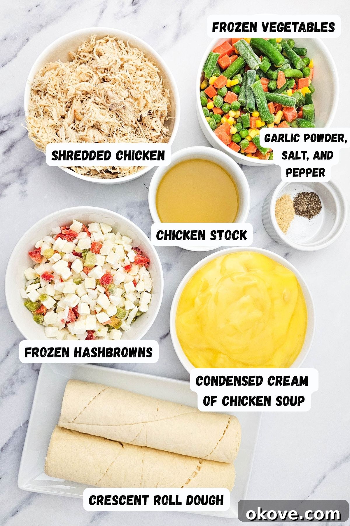 Homestyle Chicken Pot Pie Bake 3 A collection of measured ingredients laid out on a white marble surface, including crescent rolls, shredded chicken, mixed vegetables, hash browns, chicken stock, and cream of chicken soup.