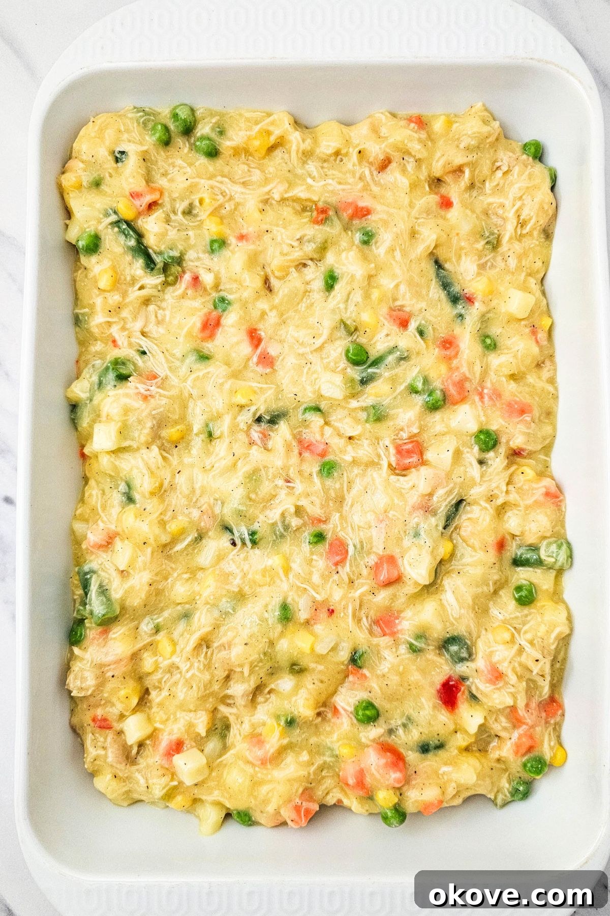 Homestyle Chicken Pot Pie Bake 6 Chicken pot pie filling spread evenly over the partially baked crescent roll crust in a rectangular white casserole dish.