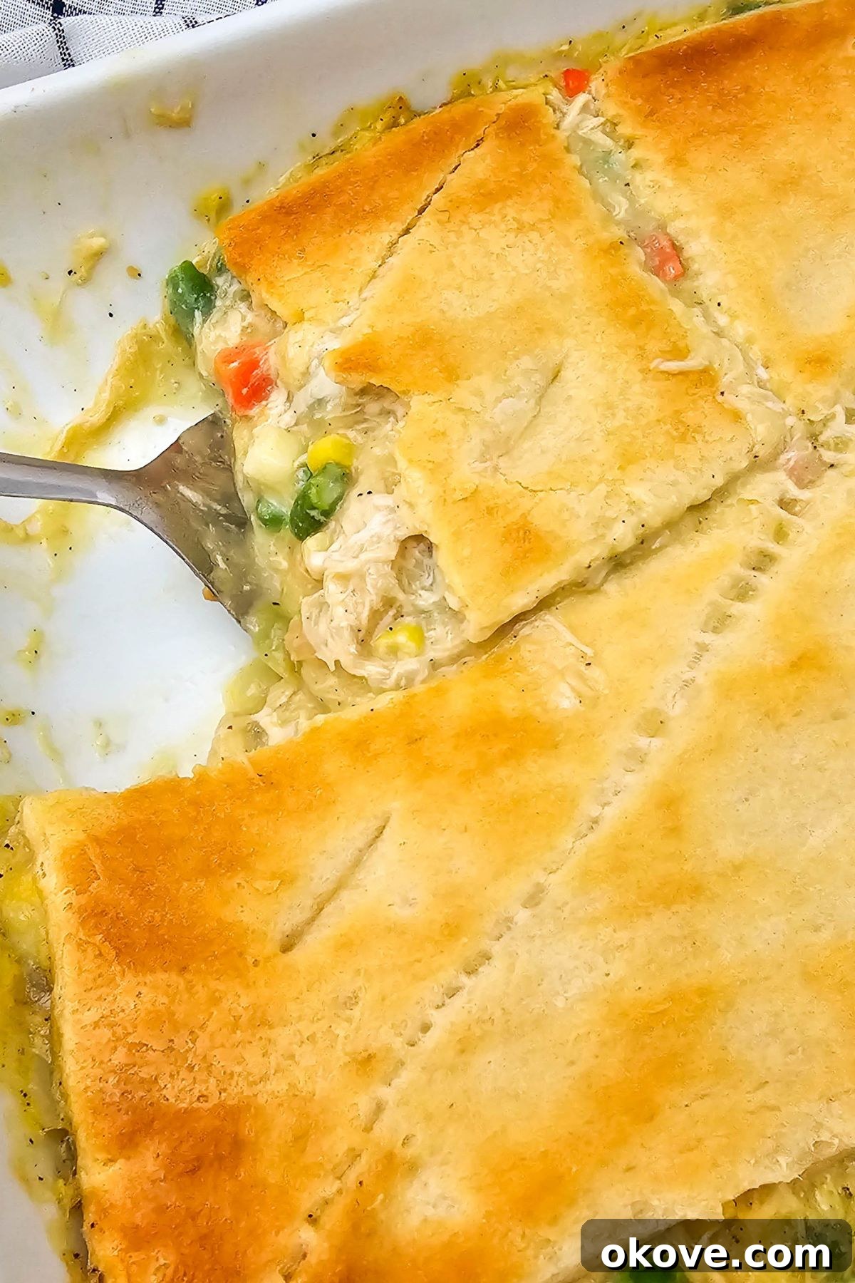 Homestyle Chicken Pot Pie Bake 10 A golden-crusted chicken pot pie casserole in a baking dish, with a spatula lifting a perfect slice, revealing the creamy filling.