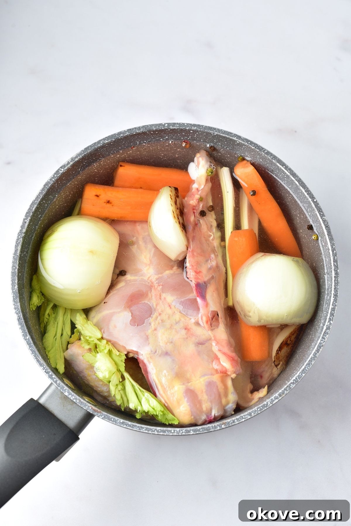 Chicken bones, charred vegetables, celery, and whole spices in a large stockpot, covered with cold water.