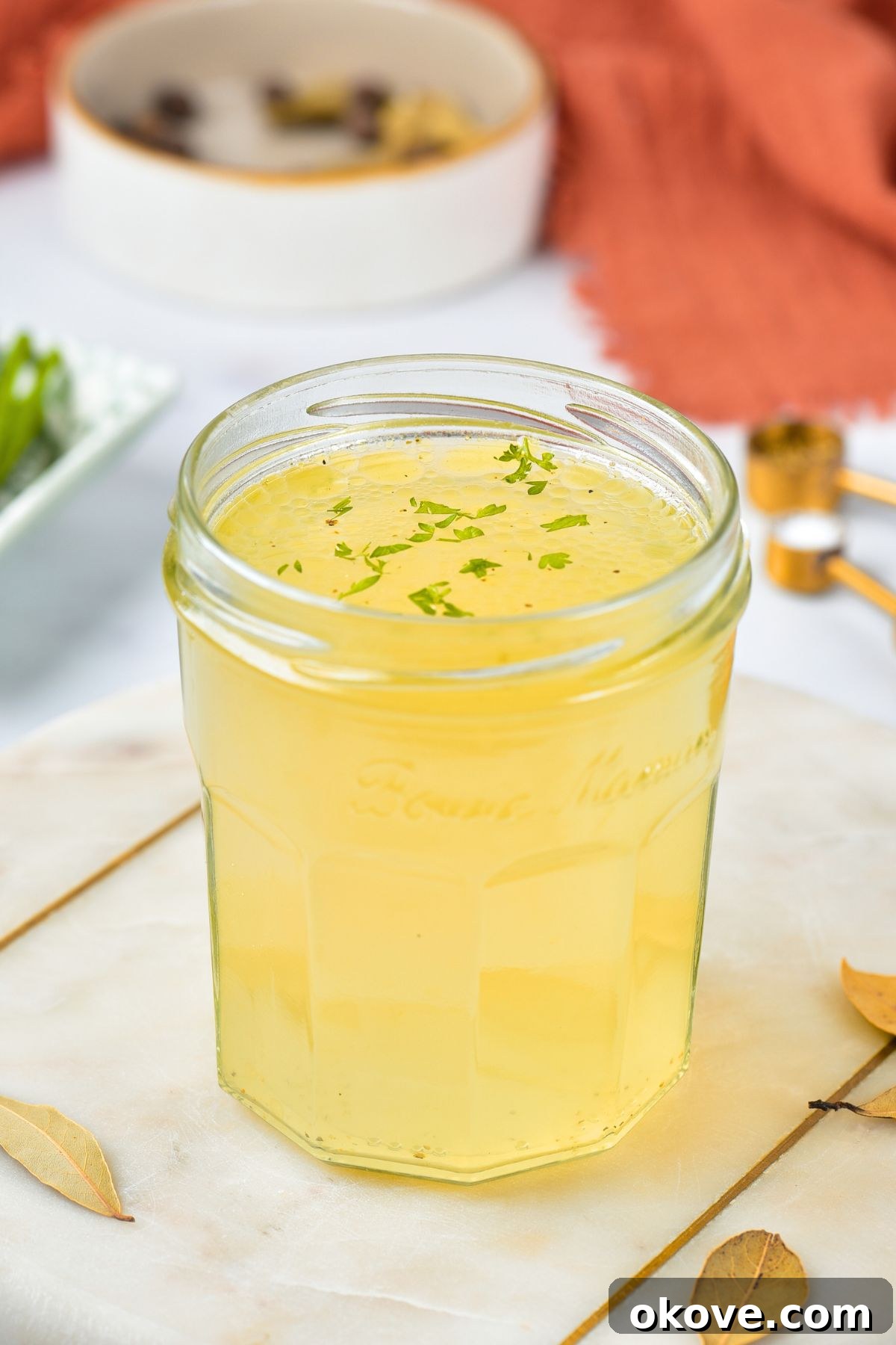 Small jar filled with golden yellow chicken stock, ready to be used in culinary creations.