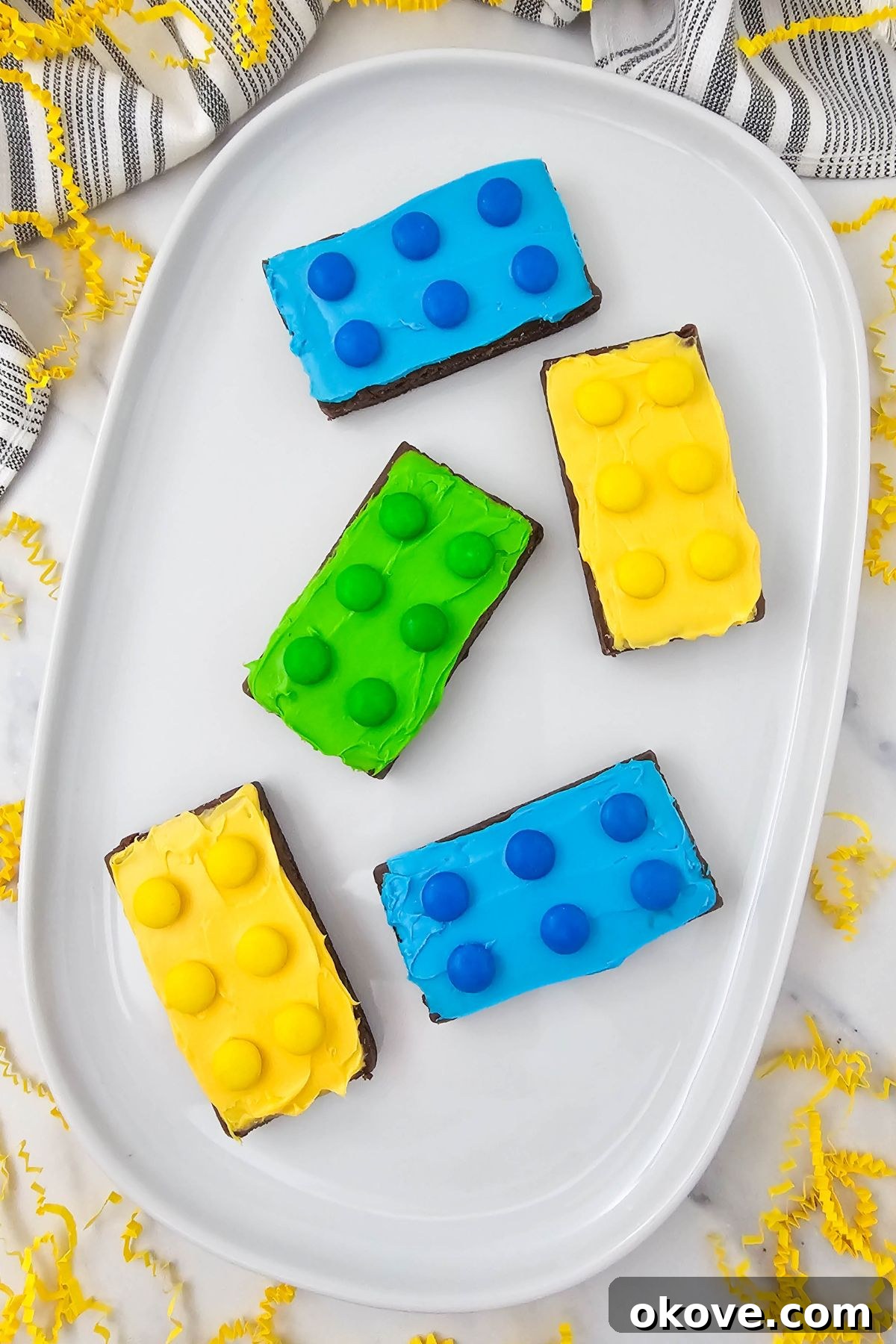 Bright and colorful brownies, frosted and topped with matching candies, resembling Lego bricks.