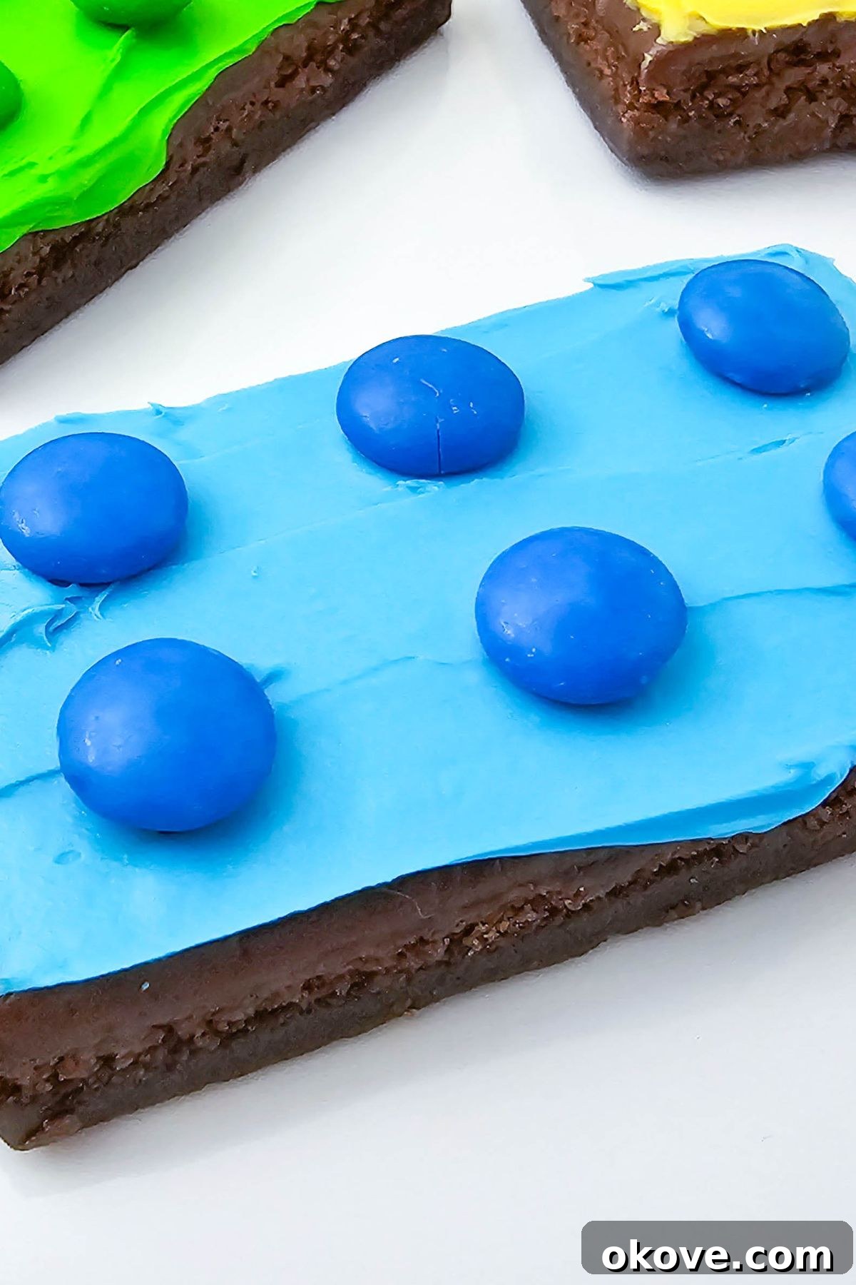 A close-up of colorful brownies topped with frosting and matching chocolate candies, ready to be served.