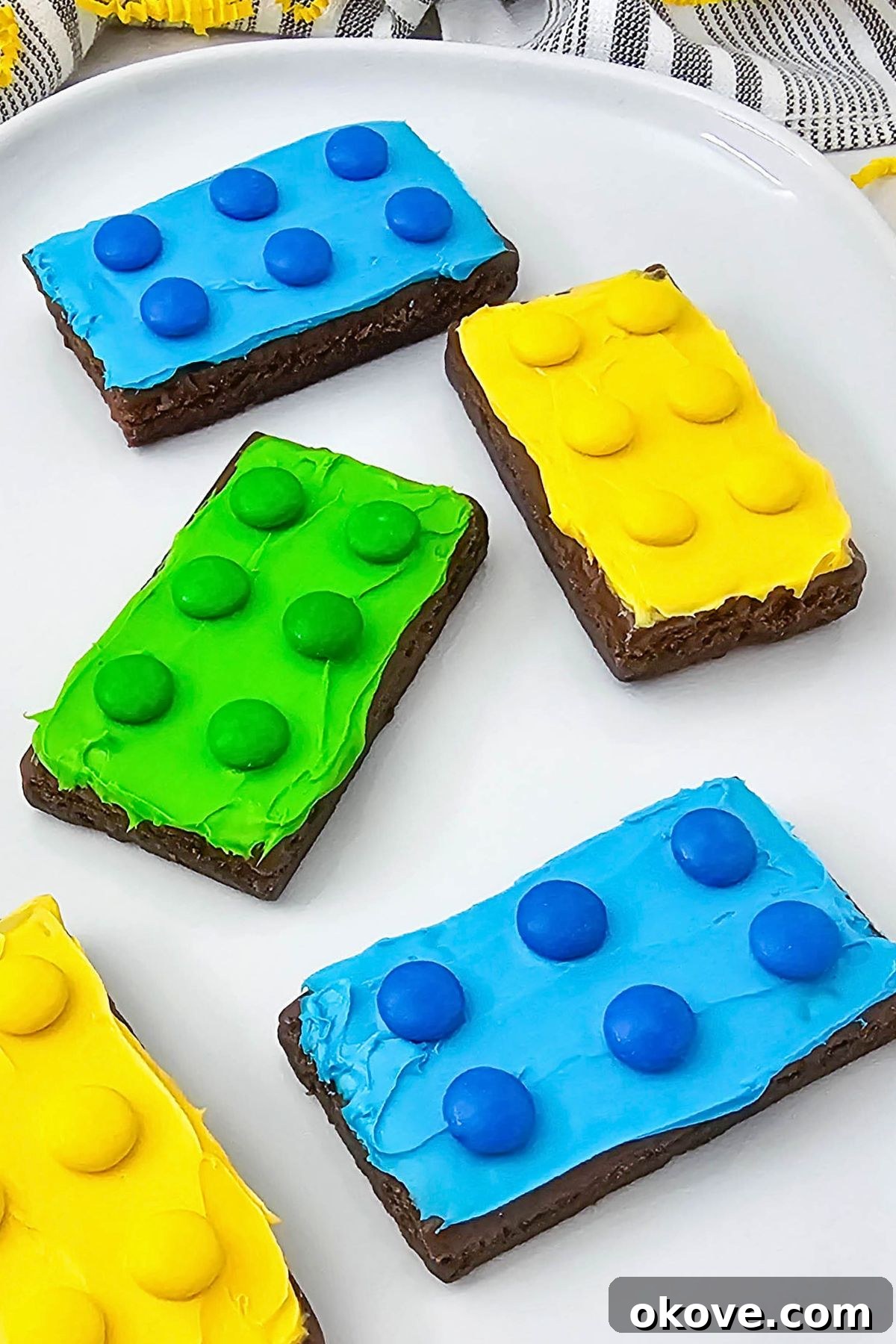 Bright and colorful brownies, frosted and topped with matching candies, displayed creatively.