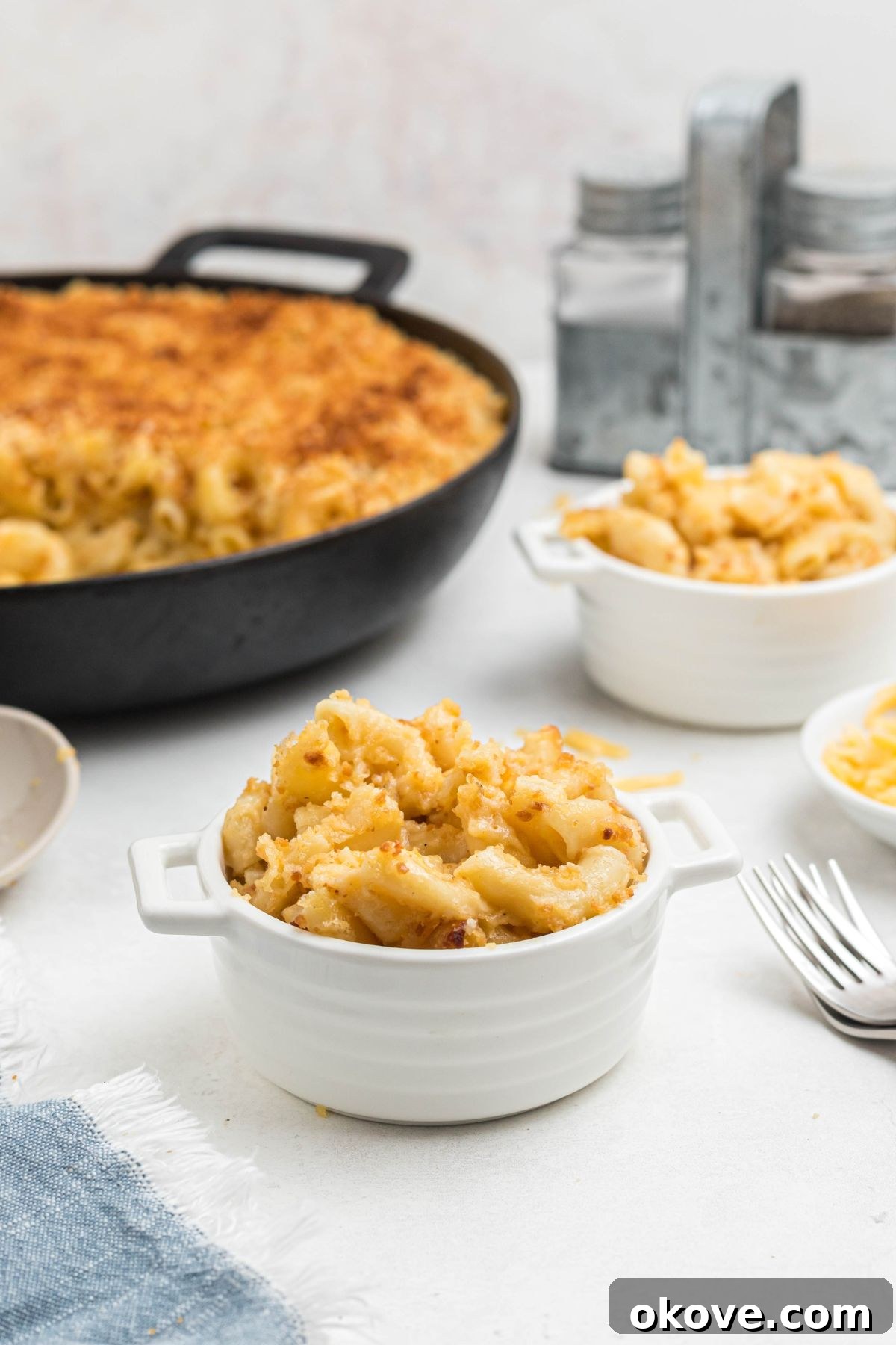 Ultimate Smoked Macaroni and Cheese Bake 2 Small white bowl of mac and cheese, served in front of the skillet, on a white marble table.