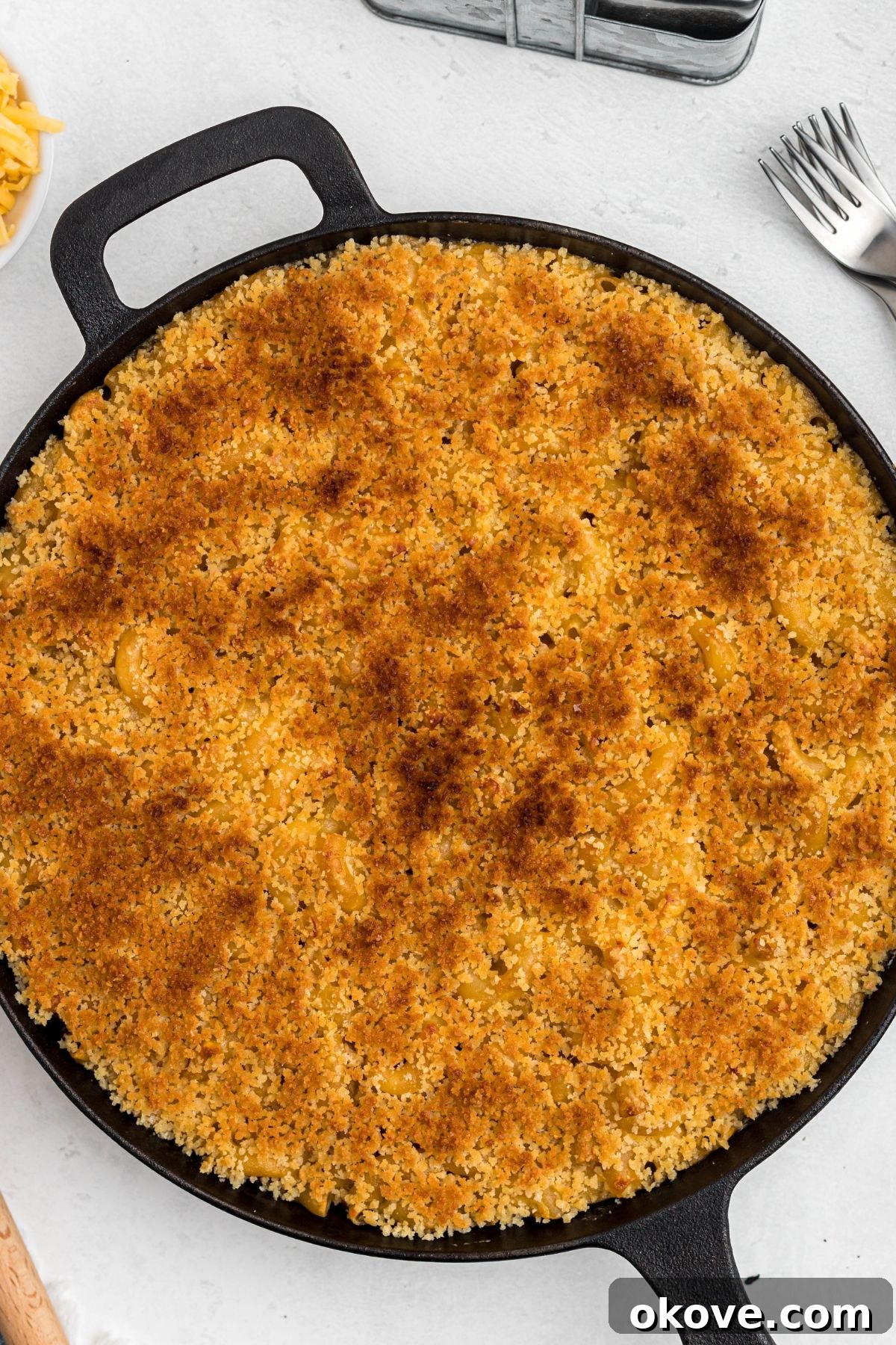 Ultimate Smoked Macaroni and Cheese Bake 11 Golden breadcrumbs on top of cast iron skillet, on a white marble table.