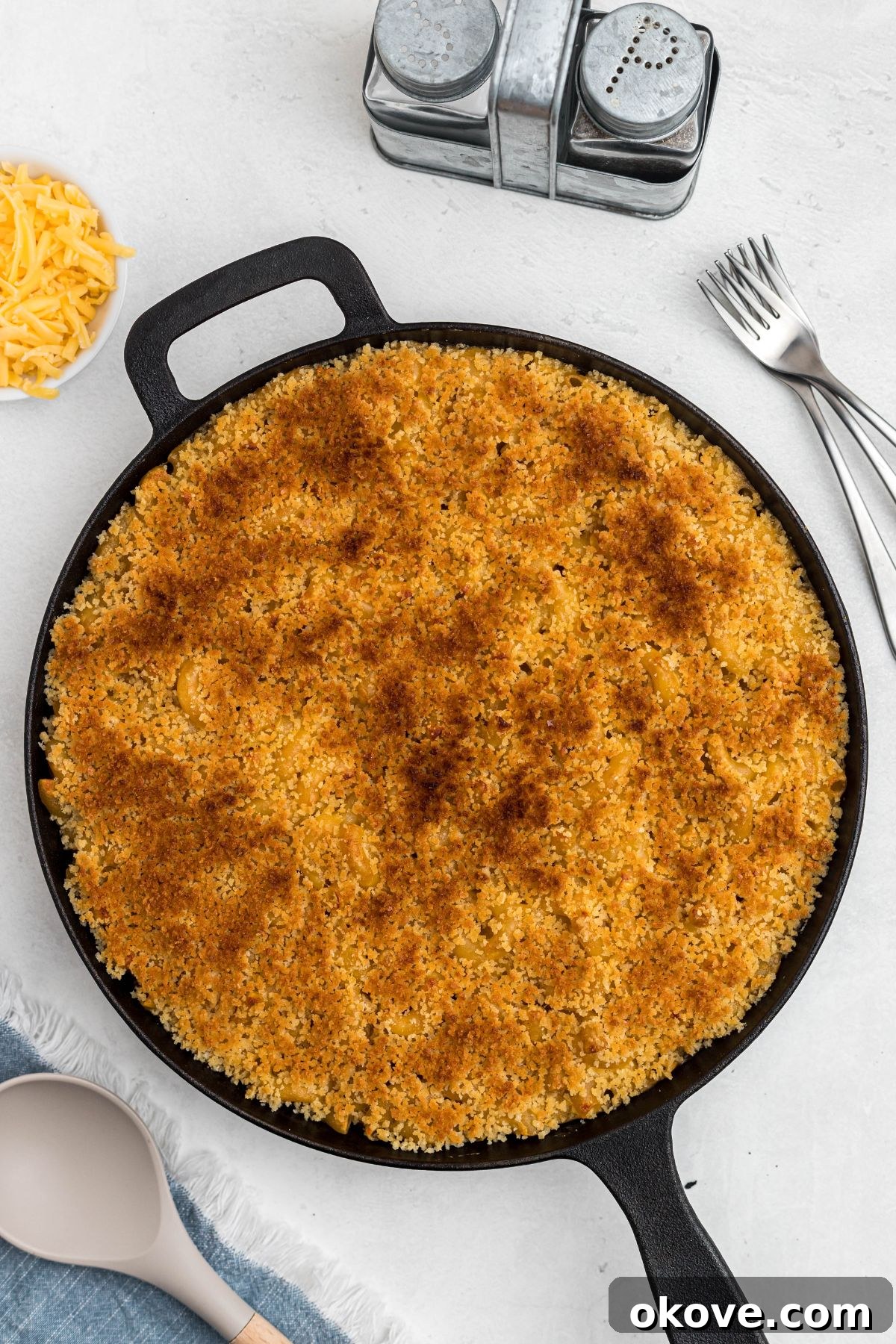 Ultimate Smoked Macaroni and Cheese Bake 12 Golden breadcrumbs on top of cast iron skillet, on a white marble table.