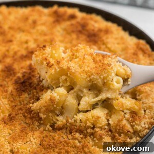 Smoked, cheesy mac and cheese in a black cast iron skillet with a spoon scooping a serving some out.