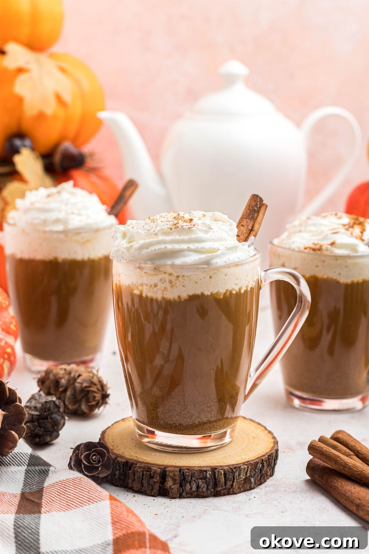 Cozy Pumpkin Spice Brew 2 Cups of coffee topped with whipped cream, in front of white pot, on a marble board. A perfect shot of cozy, homemade Pumpkin Spice Coffee ready to be enjoyed on a crisp fall day.