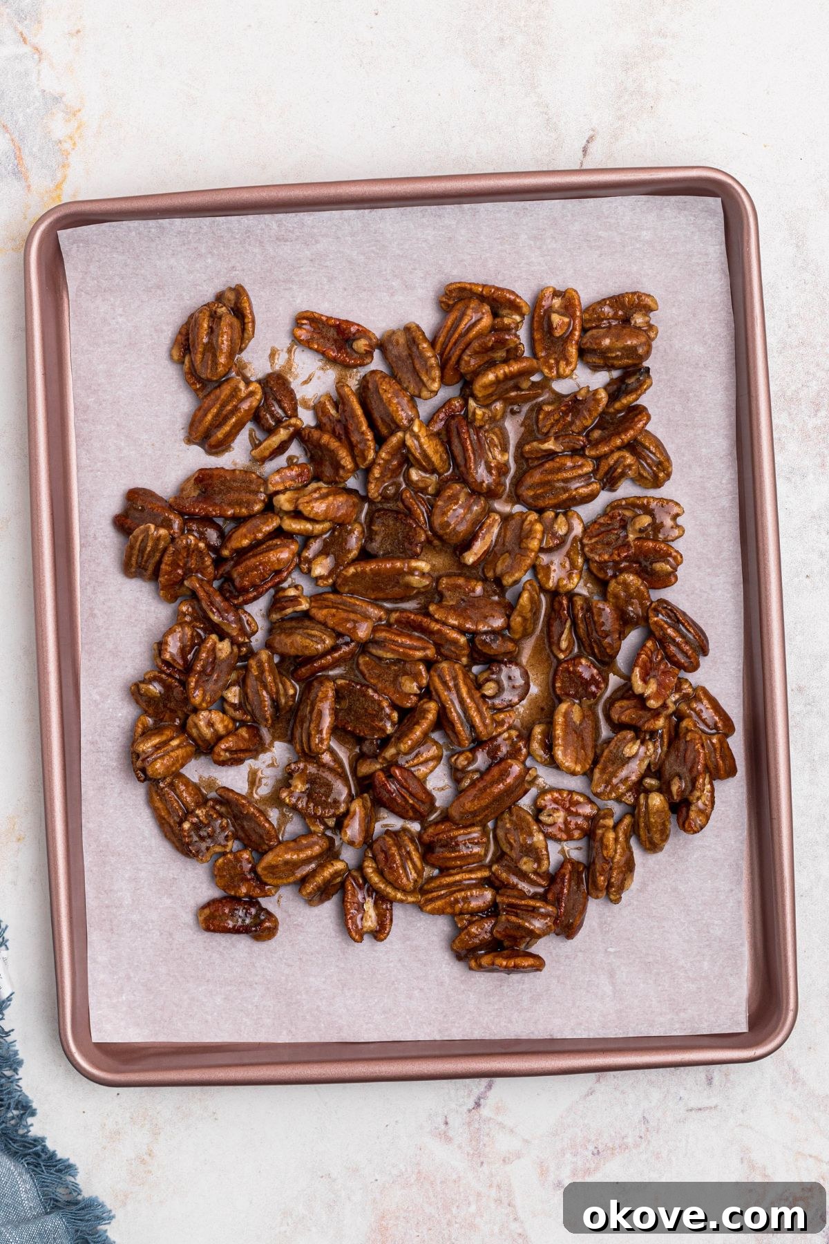 Sweet Pecan Crunch 8 Coated pecans spread onto baking sheet, lined with parchment paper, before baking. Evenly spaced pecans on a baking sheet.