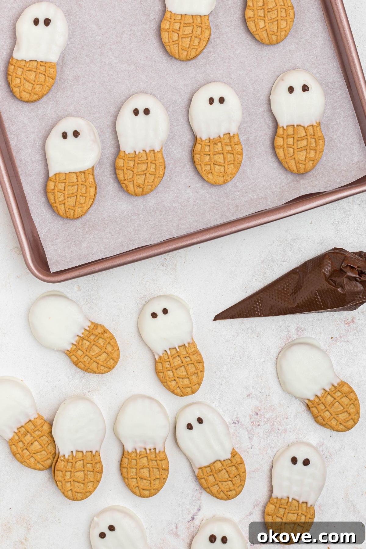 Nutter Butter Boo-tiful Bites 5 Melted milk chocolate in a piping bag adding dots for eyes onto ghost cookies.