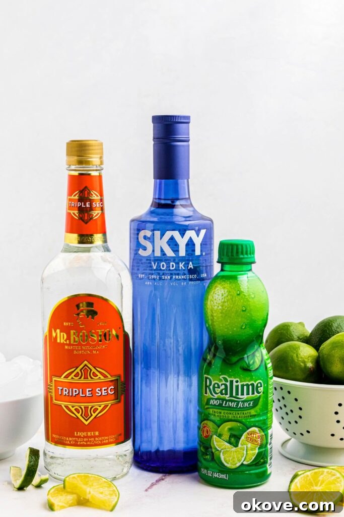 A visual spread of all ingredients required to craft delicious Kamikaze shots, neatly arranged on a pristine marble table, flanked by a bowl brimming with ice cubes and another with vibrant fresh limes.