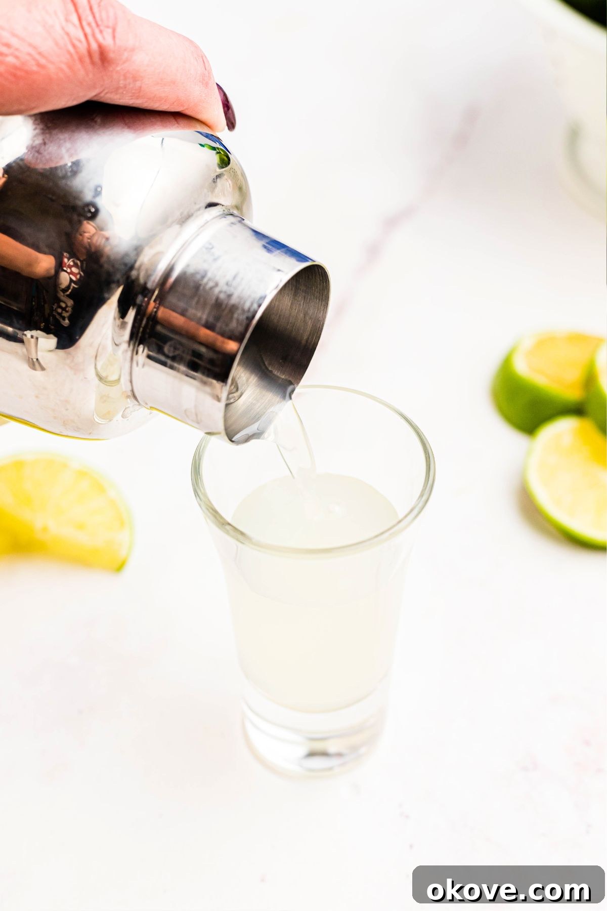 The concluding phase of crafting a Kamikaze shot, capturing the moment the expertly shaken alcohol mixture is elegantly strained and poured into a waiting shot glass, ready for immediate enjoyment.