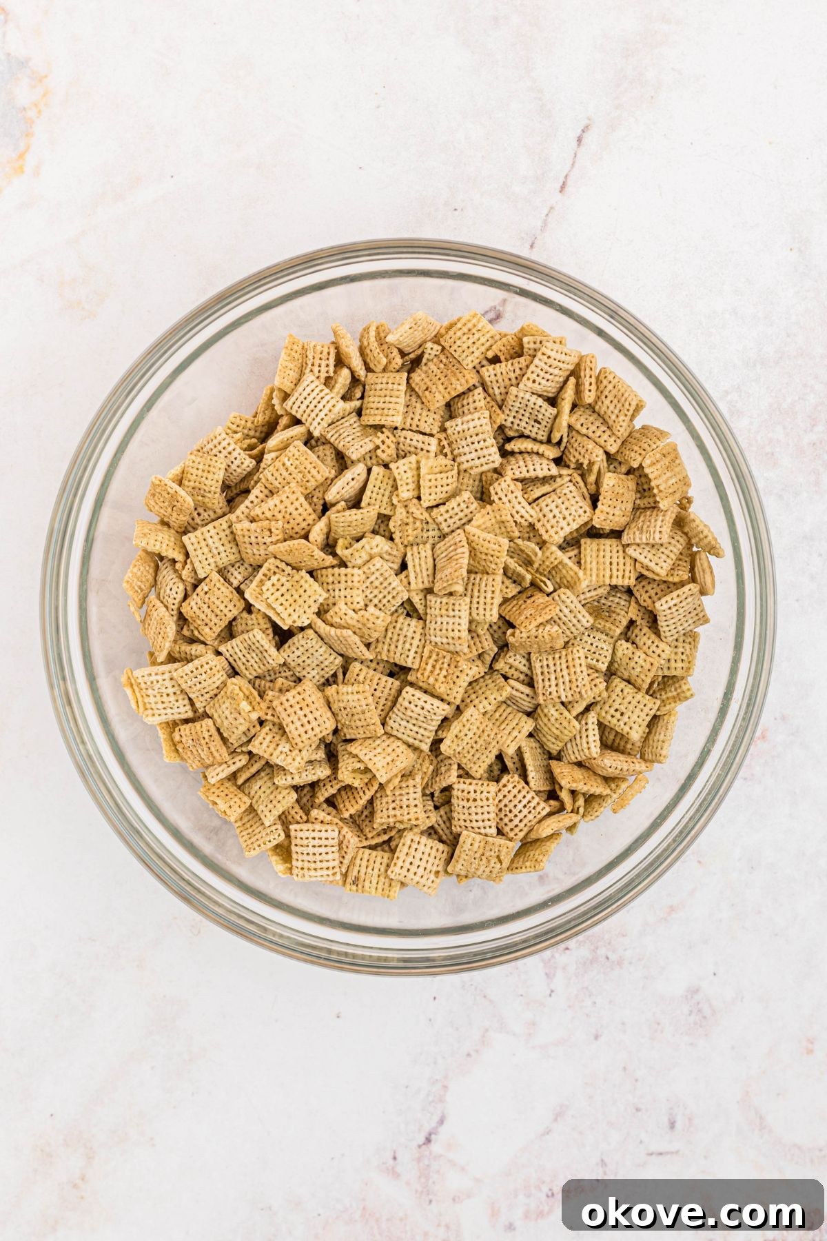 Large mixing bowl filled with rice Chex cereal. 