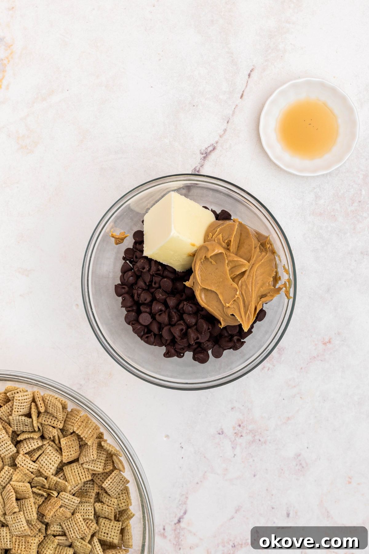 Peanut butter, chocolate, and other ingredients, in a clear microwave safe glass bowl before being melted and stirred together. 