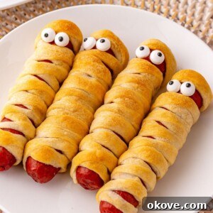 Mummy Hot Dogs 9 Mummy hot dogs on a white plate, with candy eyes.